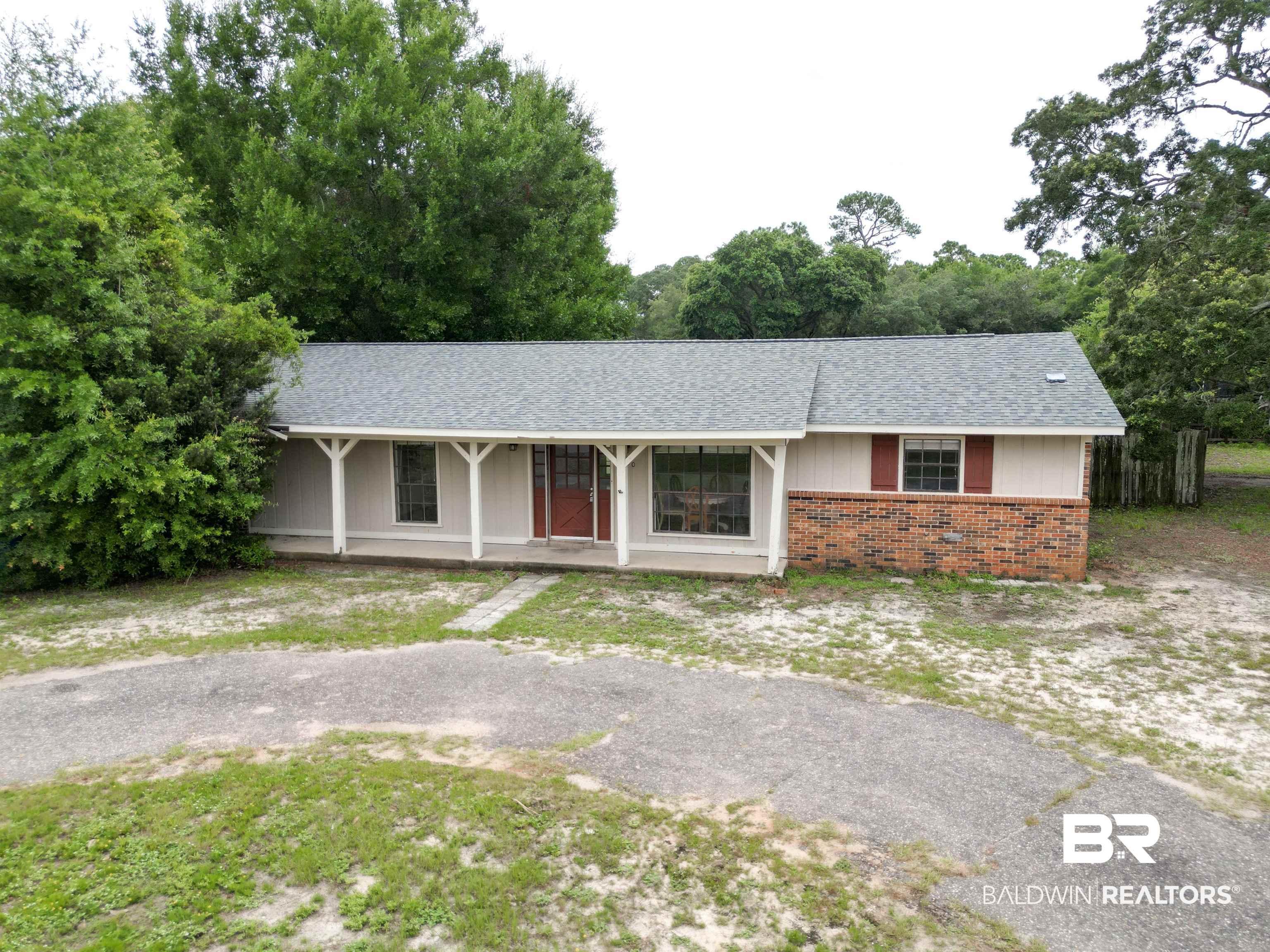 Image 2: Ranch-style exterior featuring a covered front porch with white columns, brick facade detailing, and a red front door