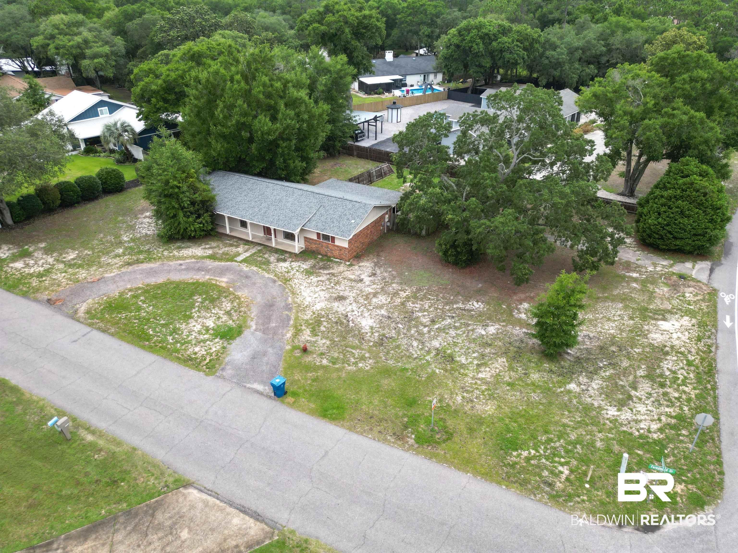 Image 4: Brick-front residence featuring a covered porch, an asphalt driveway, and a spacious lot with mature trees