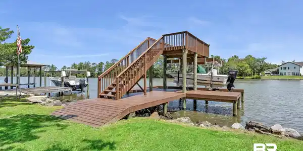 Image 2: Waterfront property featuring a multi-level boat dock with a covered slip and boat lift