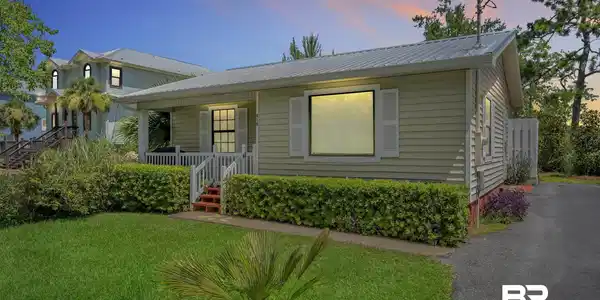 Image 3: Light green siding exterior featuring a covered porch with white railings, a metal roof, and white shutter accents