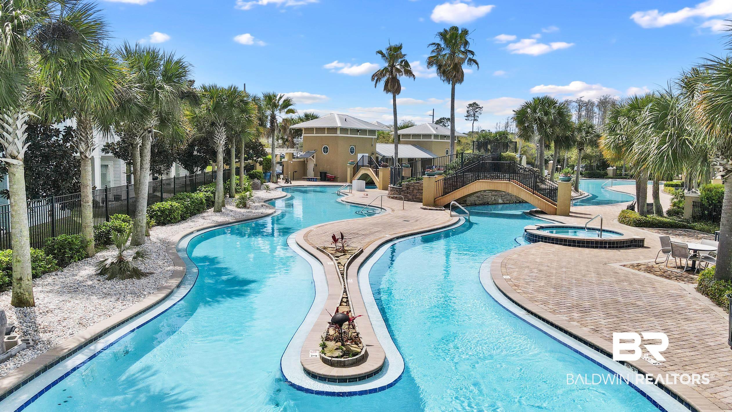 Image 3: Expansive resort-style swimming pool featuring a lazy river design, a built-in spa, paver decking, and mature palm trees