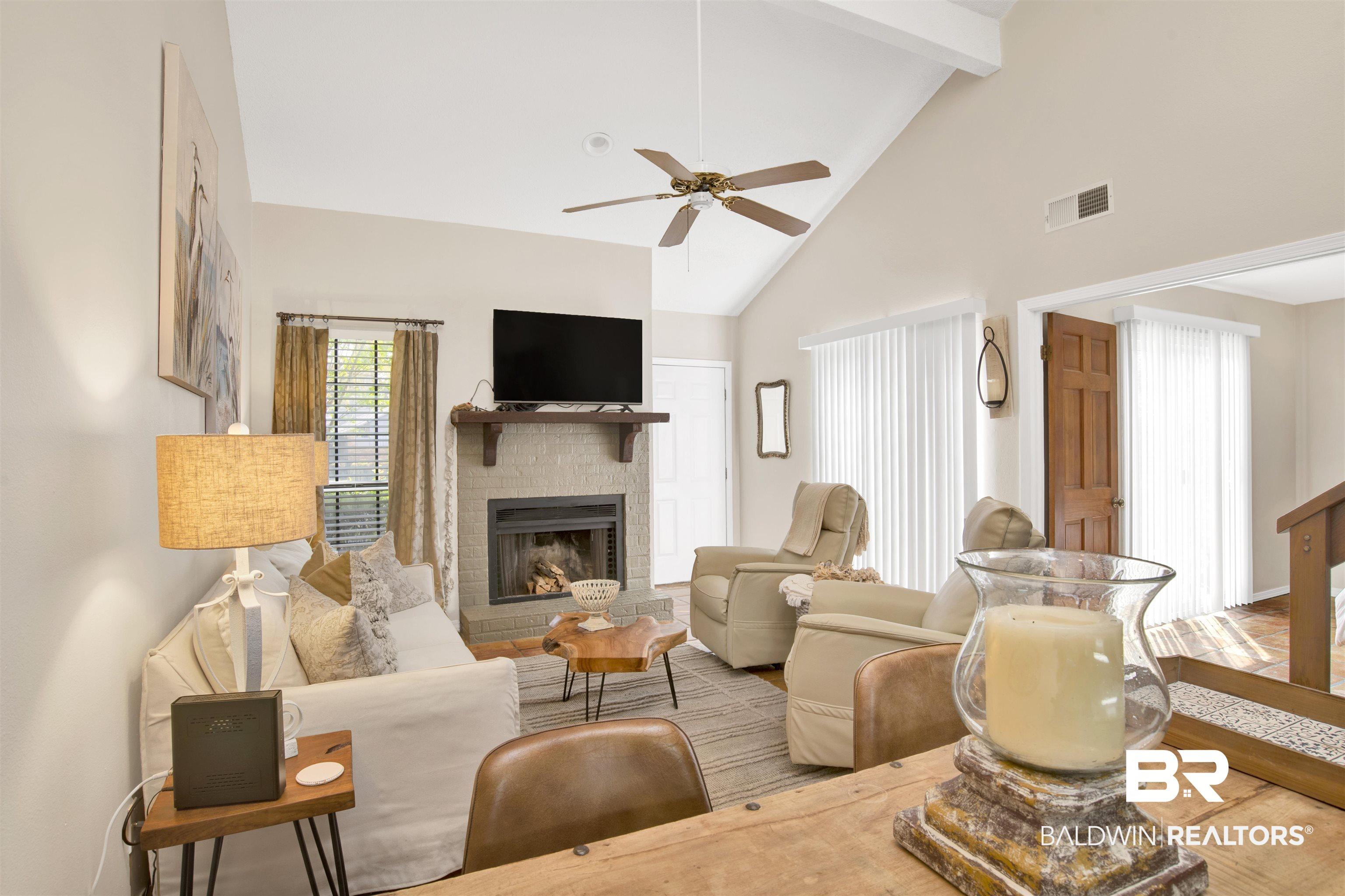 Image 4: Living room with a brick fireplace, a ceiling fan, lofted ceiling, and wood finished floors