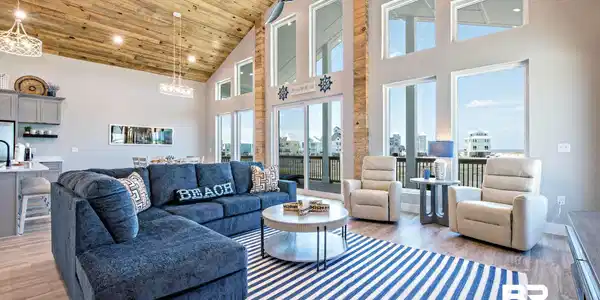 Image 2: Vaulted wood-finish ceiling complementing an open-concept living area with extensive windows