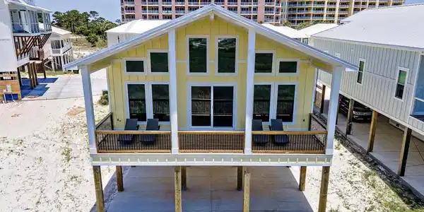 Image 3: Yellow exterior with white trim, featuring a covered front porch with dark railing