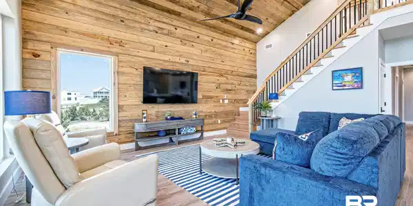 Image 4: Vaulted ceiling with wood-finish planks, accent wall featuring horizontal wood paneling, open staircase with wood handrails and black balusters, recessed lighting, and wood-finish flooring