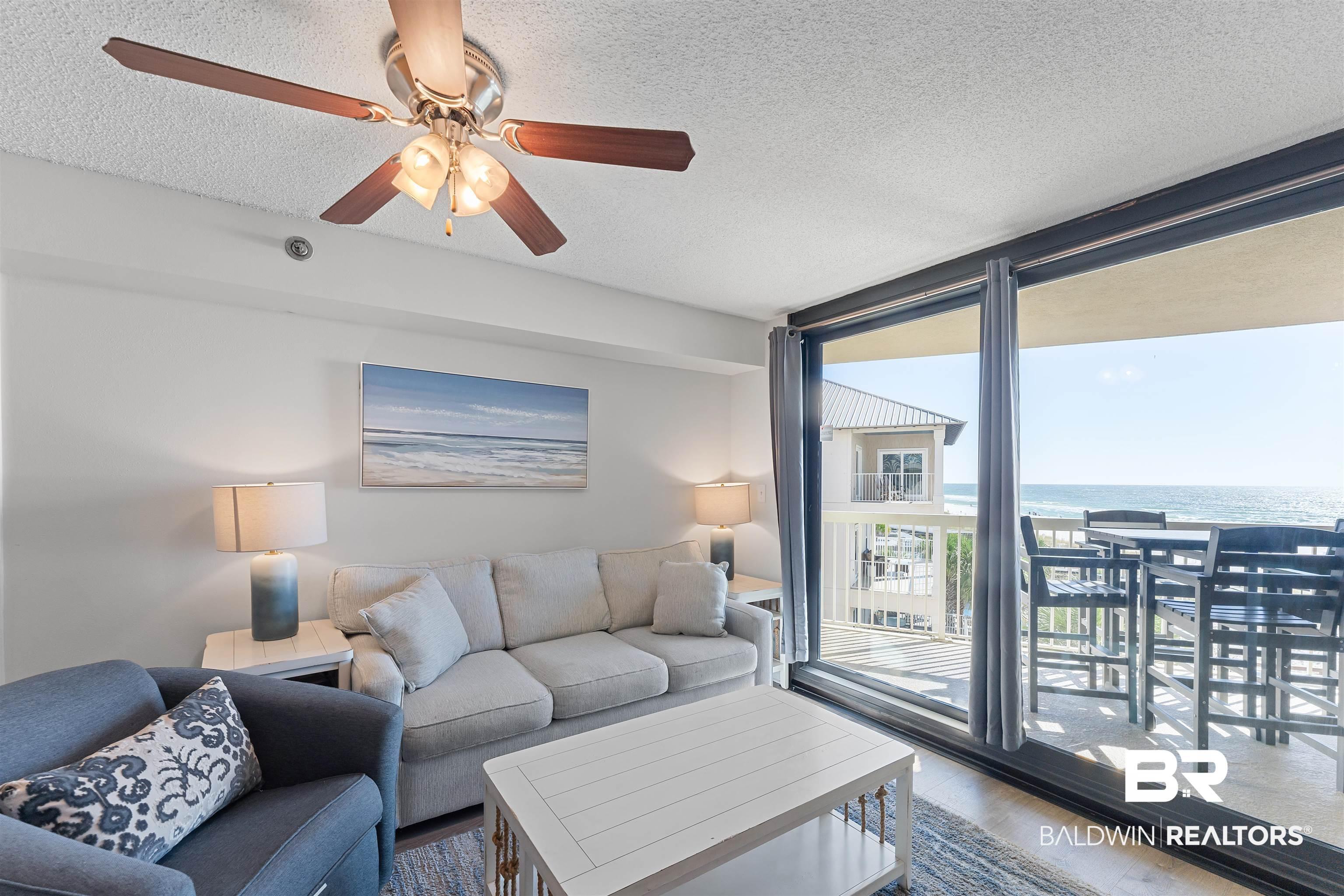 Image 2: Living room with wood finished floors, a water view, a textured ceiling, expansive windows, and ceiling fan