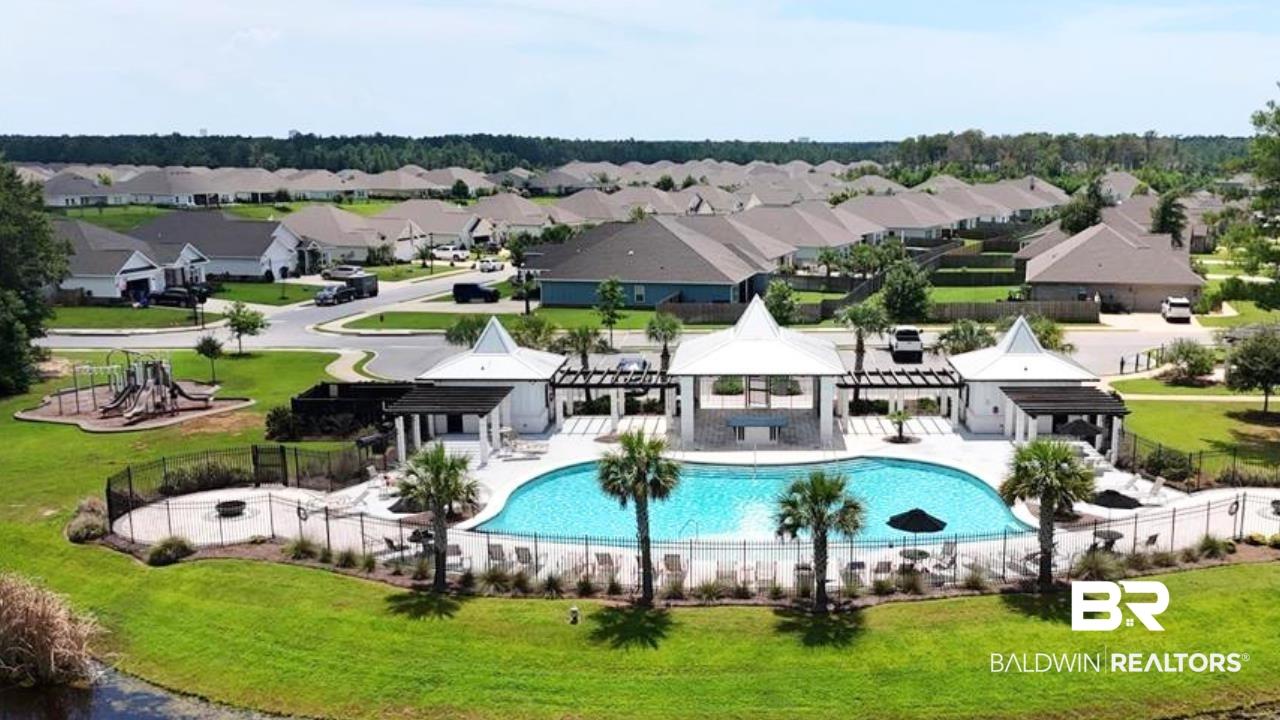 Image 2: Central community amenity area featuring a fenced swimming pool with surrounding lounge seating, a covered pavilion with bar seating, and an additional covered structure