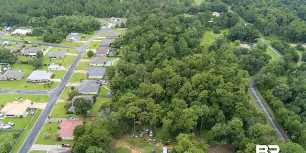 Image 4: Aerial view of residential area featuring a heavily wooded area
