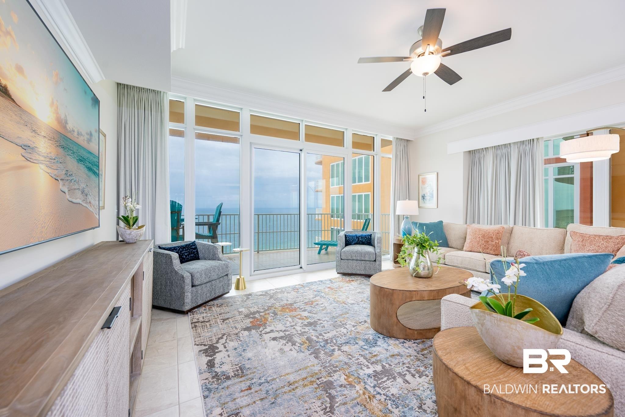 Image 3: Spacious living area featuring floor-to-ceiling sliding glass doors, a modern ceiling fan, crown molding, and tiled flooring