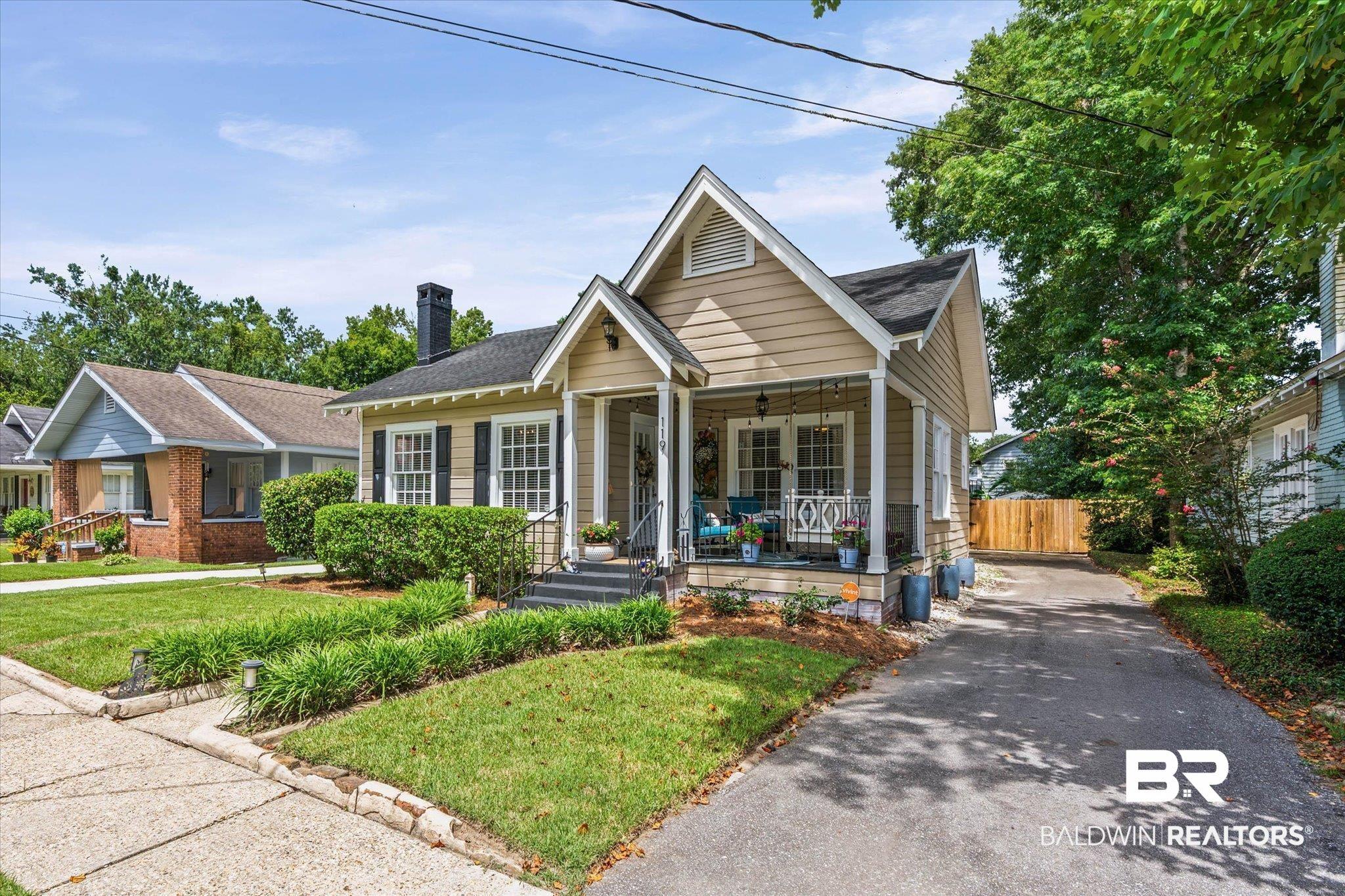 Image 2: Craftsman-style home featuring a covered front porch, light-colored siding, and black window shutters