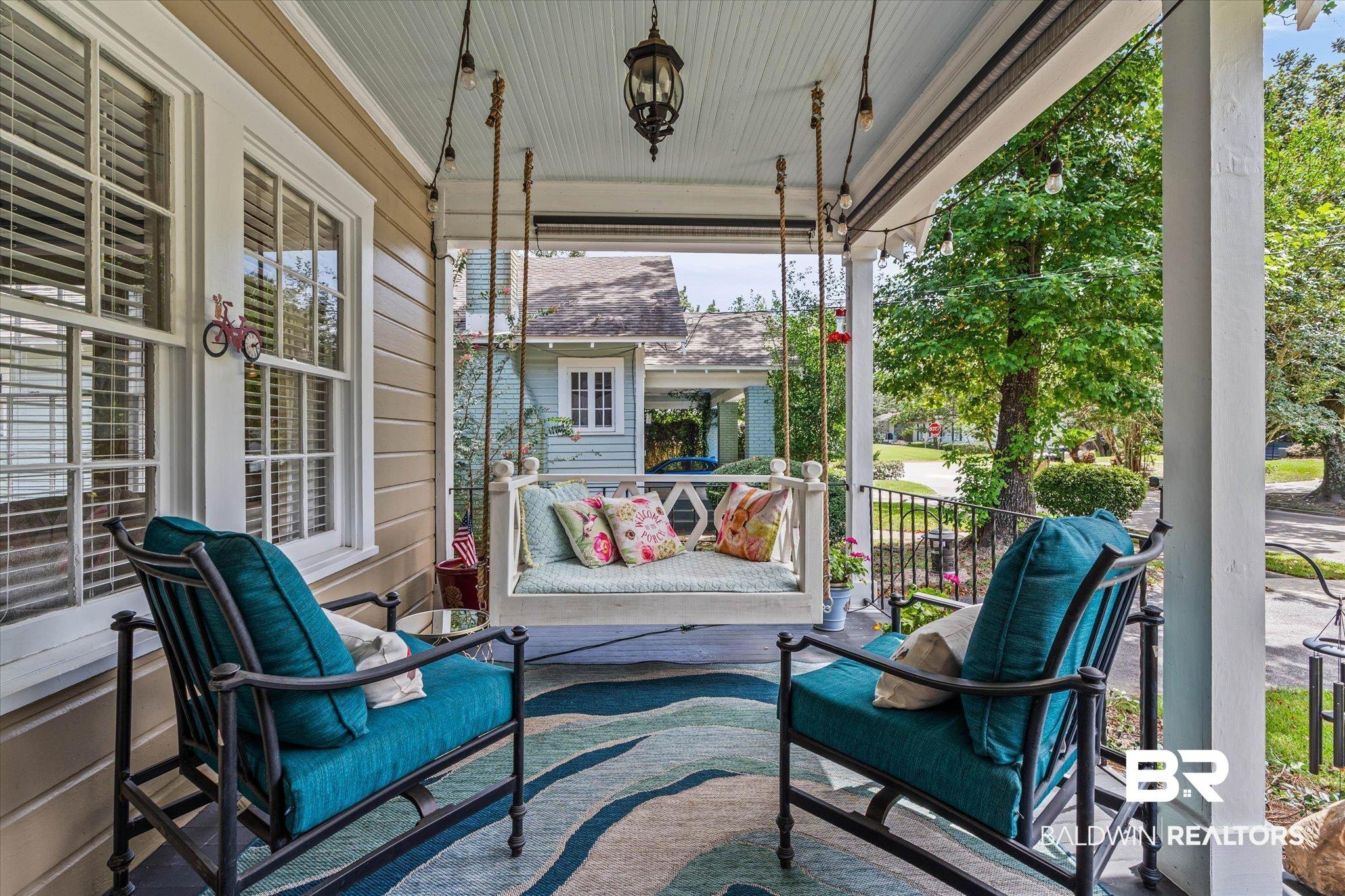 Image 3: Inviting covered porch featuring a painted ceiling, decorative light fixture, and a porch swing