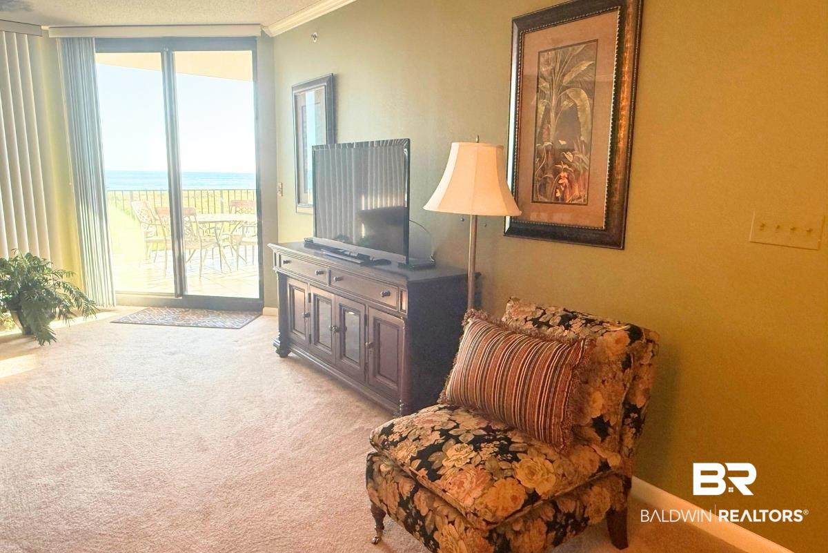 Image 4: Living area featuring light colored carpet, crown molding, and a wall of windows