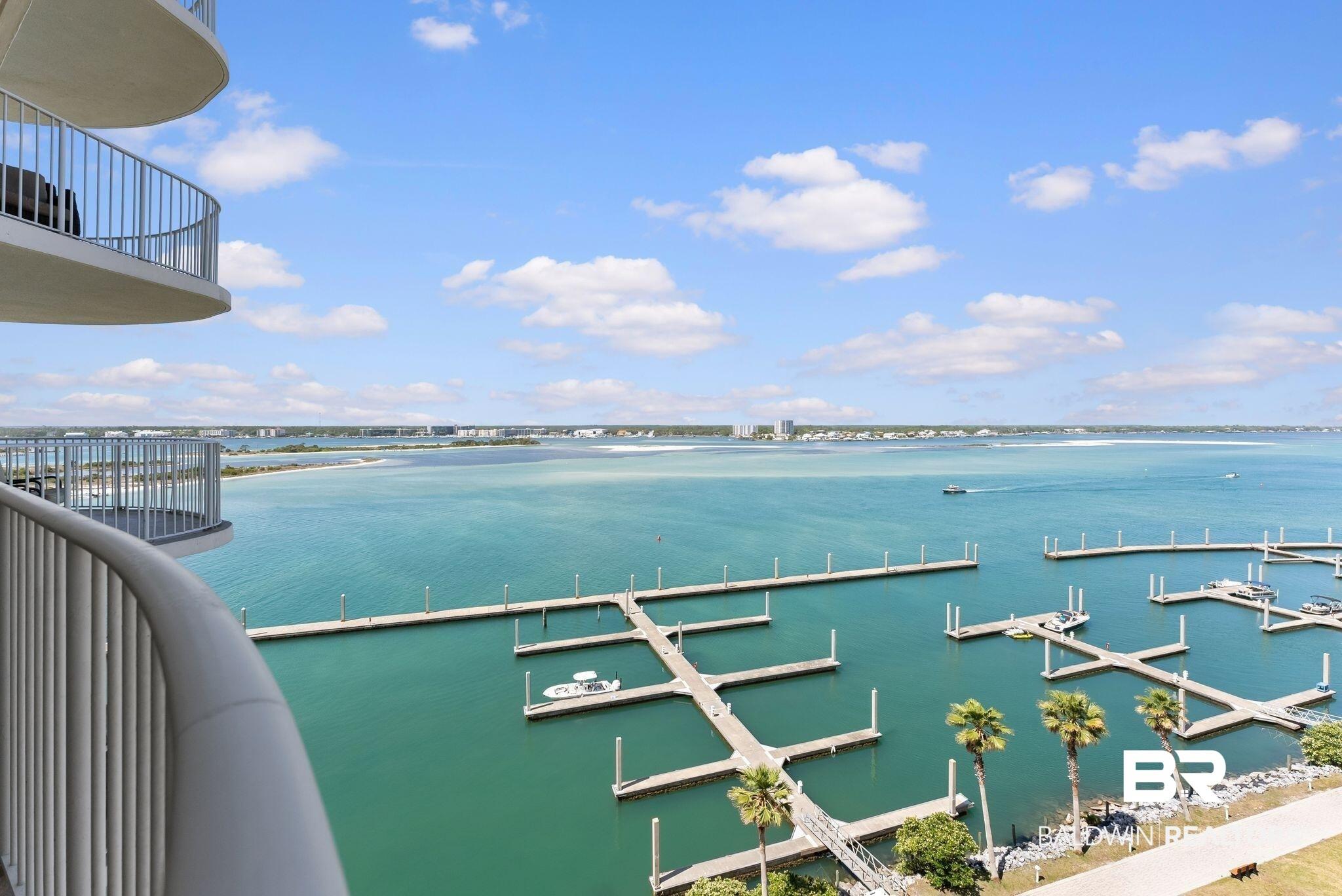 Image 2: Curved balcony with metal railings offering expansive water views, boat slips, and distant shoreline