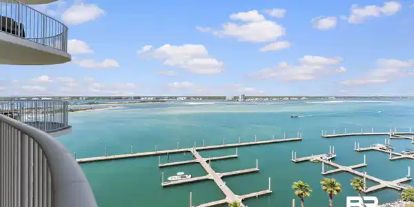 Image 2: Curved balcony with metal railings offering expansive water views, boat slips, and distant shoreline