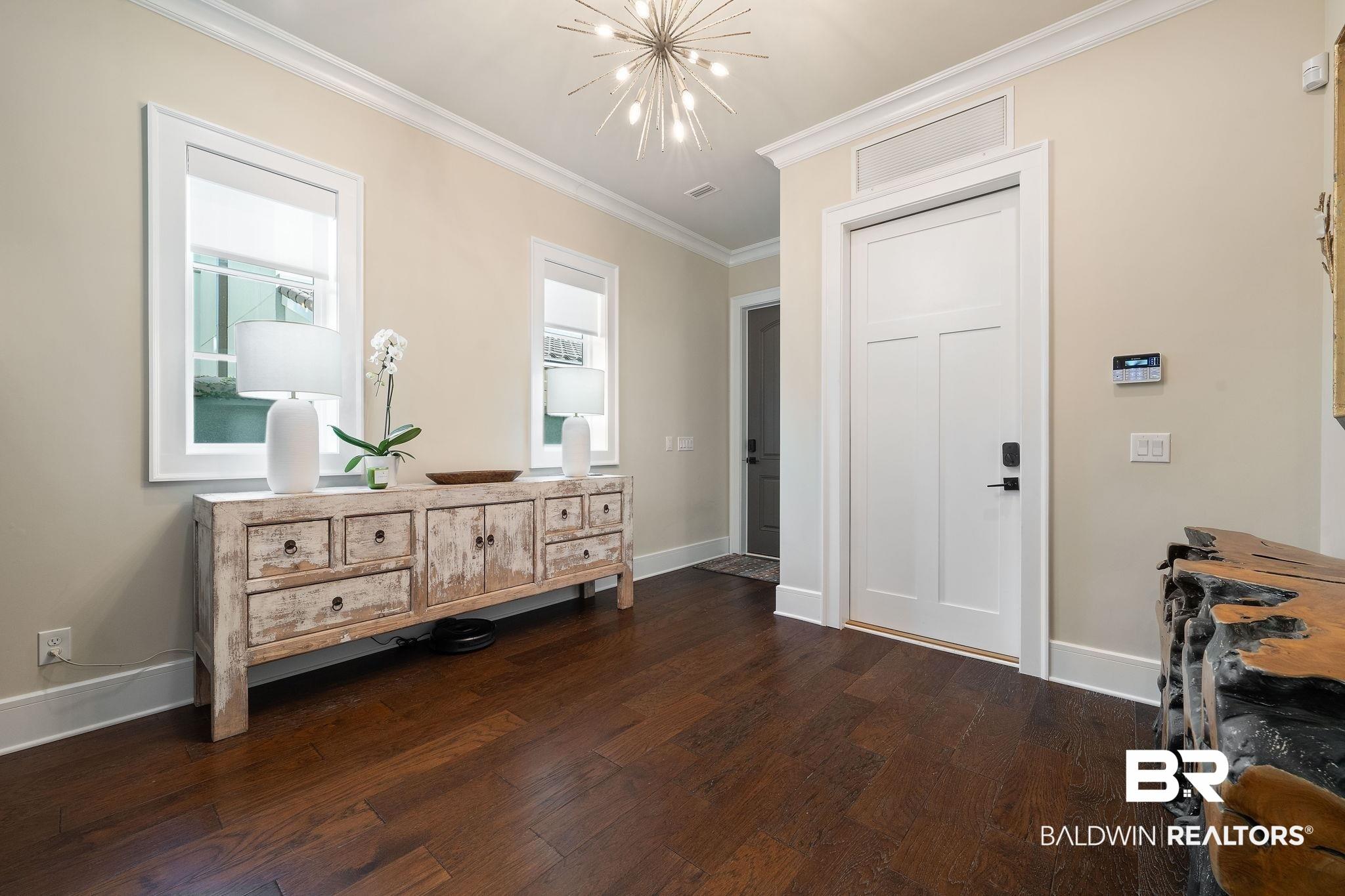 Image 4: Entrance foyer featuring dark wood-type flooring, ornamental molding, and a chandelier