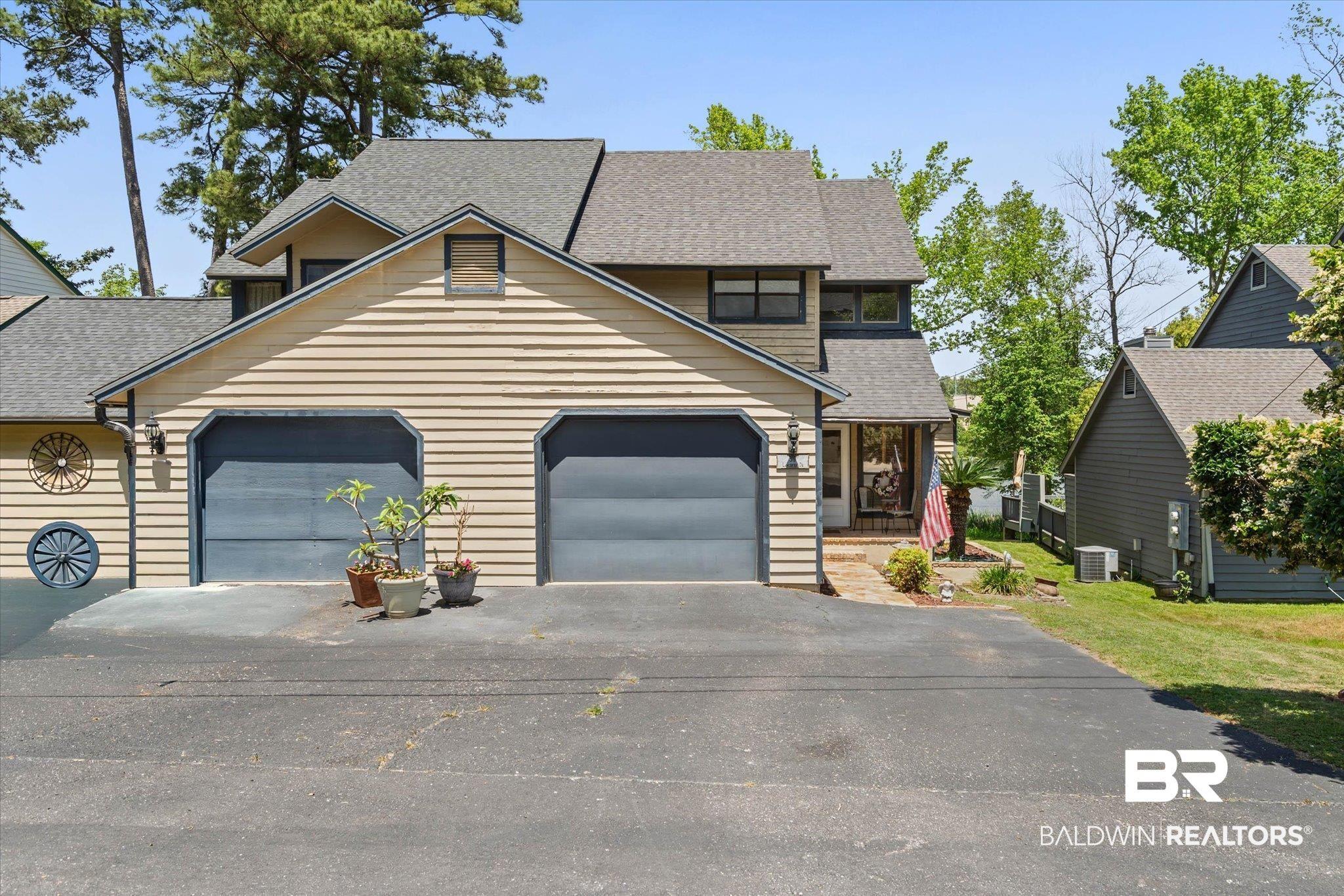 Image 2: Two-story property featuring horizontal siding, a gabled roofline, and an attached two-car garage with dark gray doors