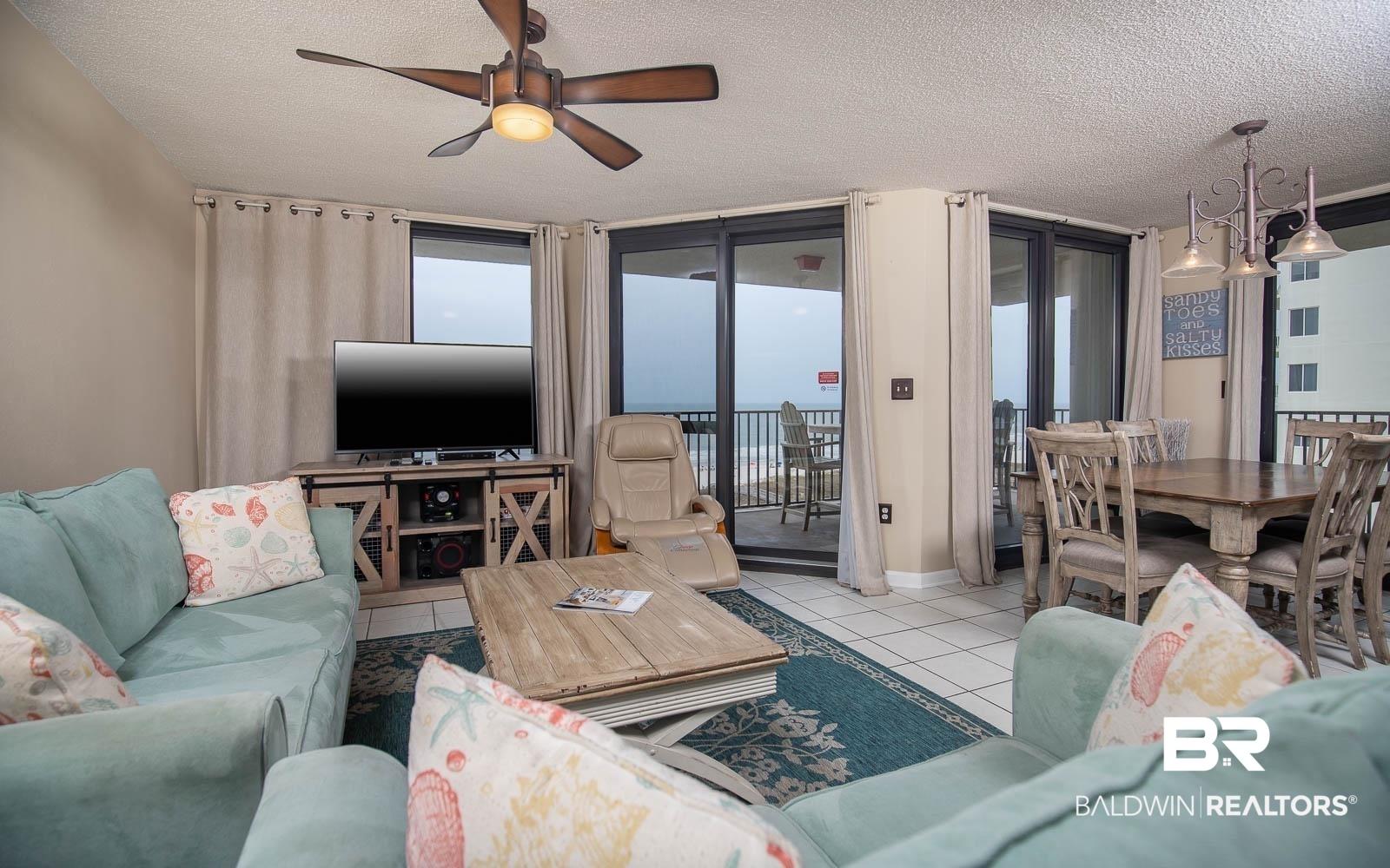 Image 4: Open living area with ceramic tile flooring, a ceiling fan, and sliding glass doors opening to a balcony