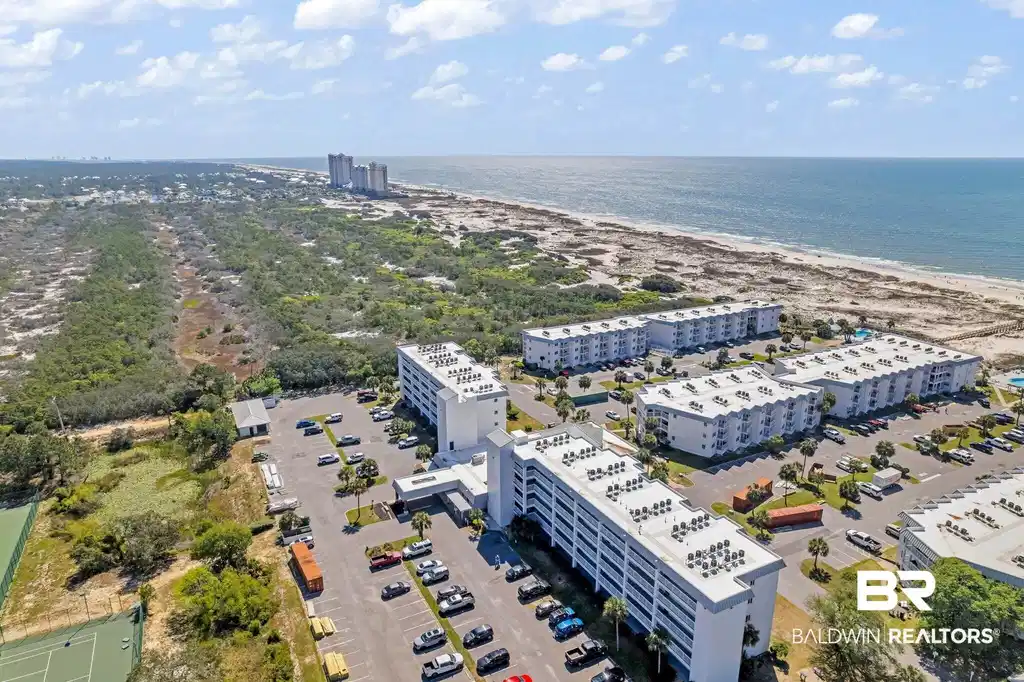 Image 1: Coastal condominium complex with multiple buildings, surface parking, and tennis courts