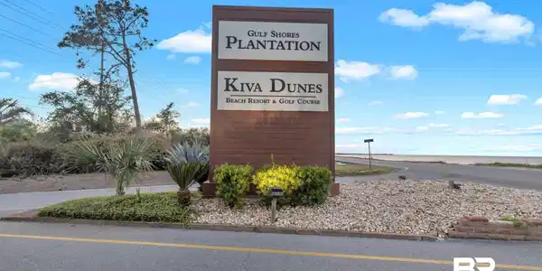 Image 2: Wood-finish signage with prominent lettering, set against a backdrop of mature trees and landscaping