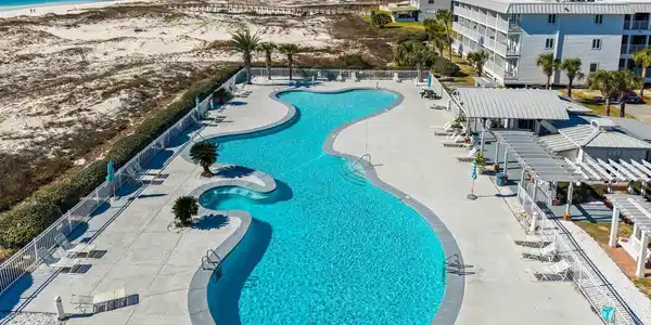 Image 3: Expansive serpentine swimming pool with integrated spa, surrounded by a paved deck