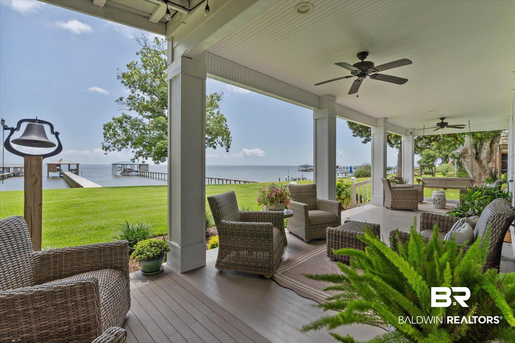 Image 3: Spacious covered porch with wood-finish flooring, white columns, and ceiling fans