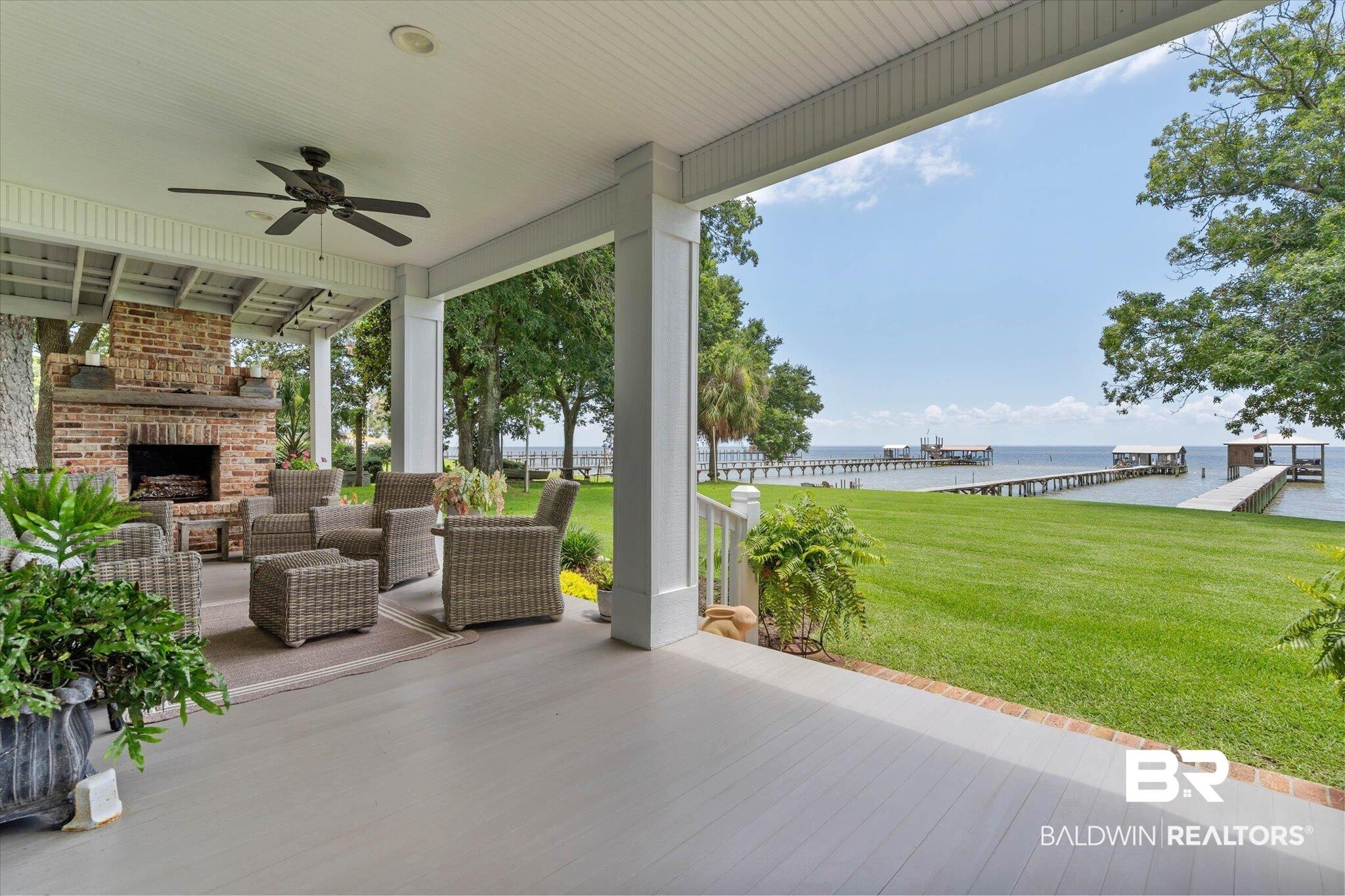 Image 4: Expansive covered porch featuring a brick fireplace, ceiling fan, and painted wood flooring