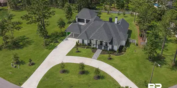 Image 3: White exterior residence with a dark shingled roof and a multi-car concrete driveway