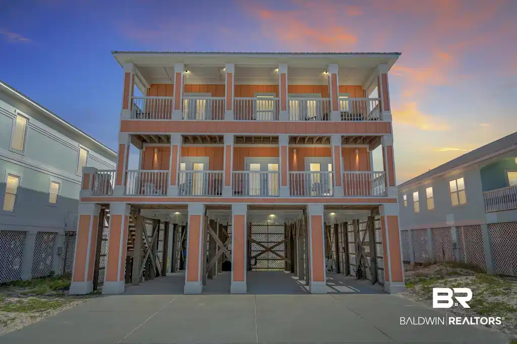 Image 1: Three-story stilt home featuring multiple balconies with white railings, a concrete drive, and an exposed foundation with X-pattern cross bracing