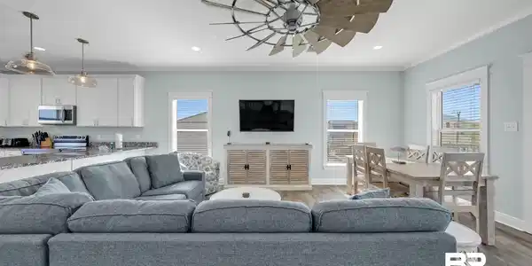 Image 3: Open-concept living space featuring wood-finish flooring, a contemporary ceiling fan, and multiple windows