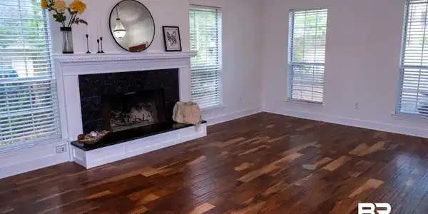 Image 2: Spacious room featuring vaulted ceilings, a prominent fireplace with a white mantel and dark tile surround, and rich wood-finish flooring
