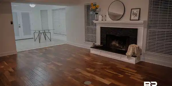 Image 3: Spacious living area featuring rich wood-finish flooring and a fireplace with a white mantel and dark stone surround