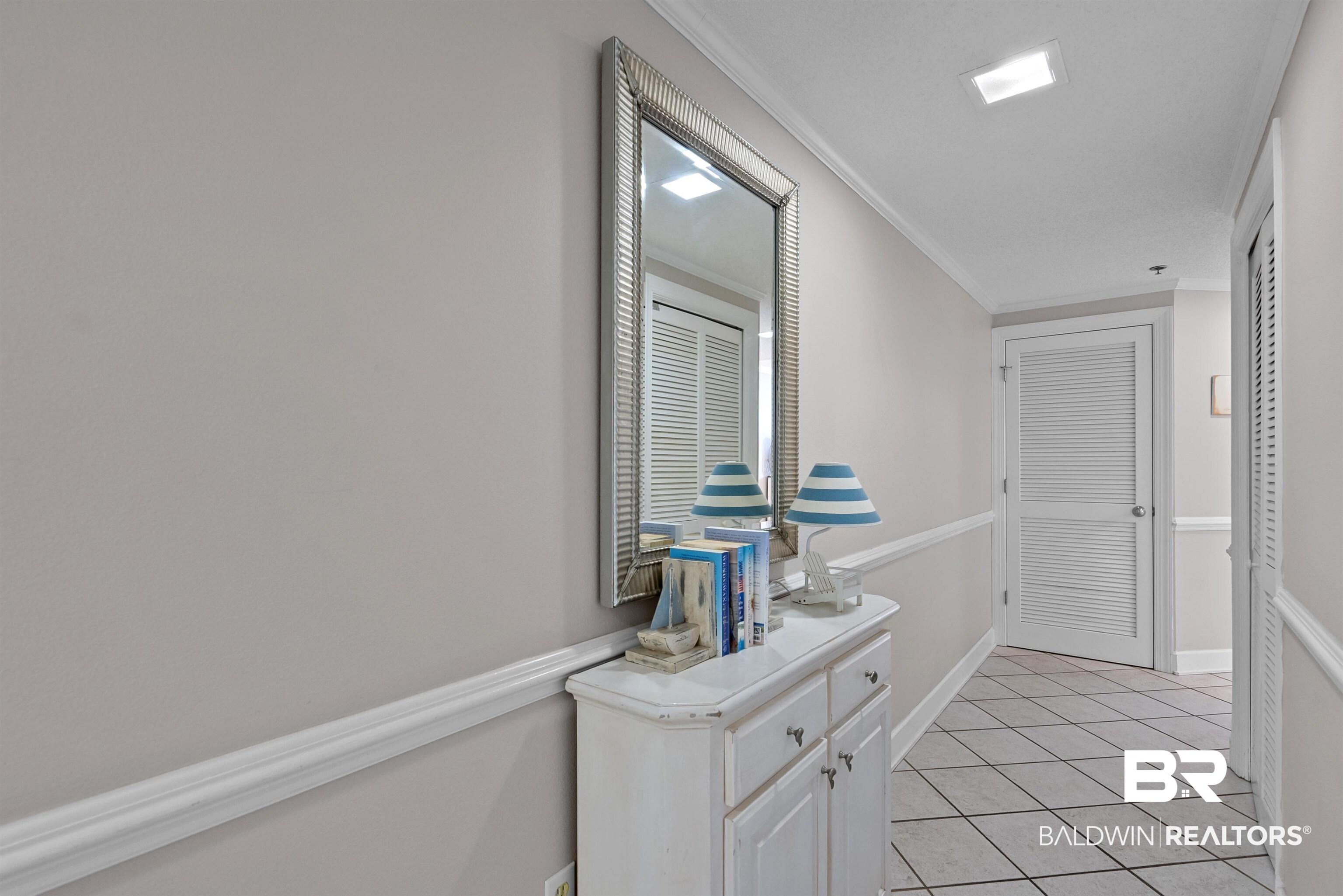 Image 2: Hallway featuring light gray walls with chair rail molding, square tile flooring laid in a diagonal pattern, and recessed ceiling lighting