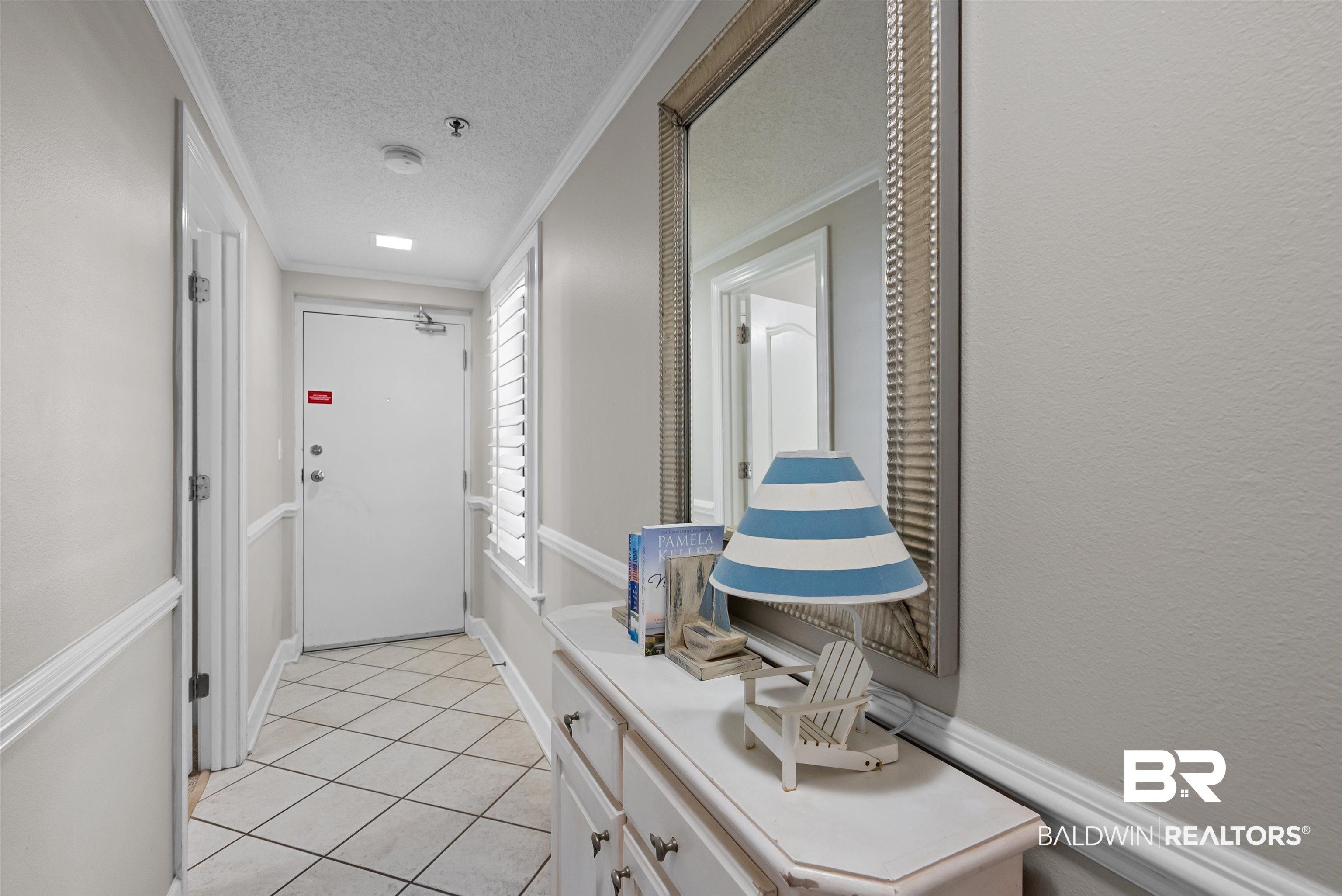 Image 3: Entryway featuring diamond-patterned floor tiling, an accent mirror, and a built-in console table with cabinet storage