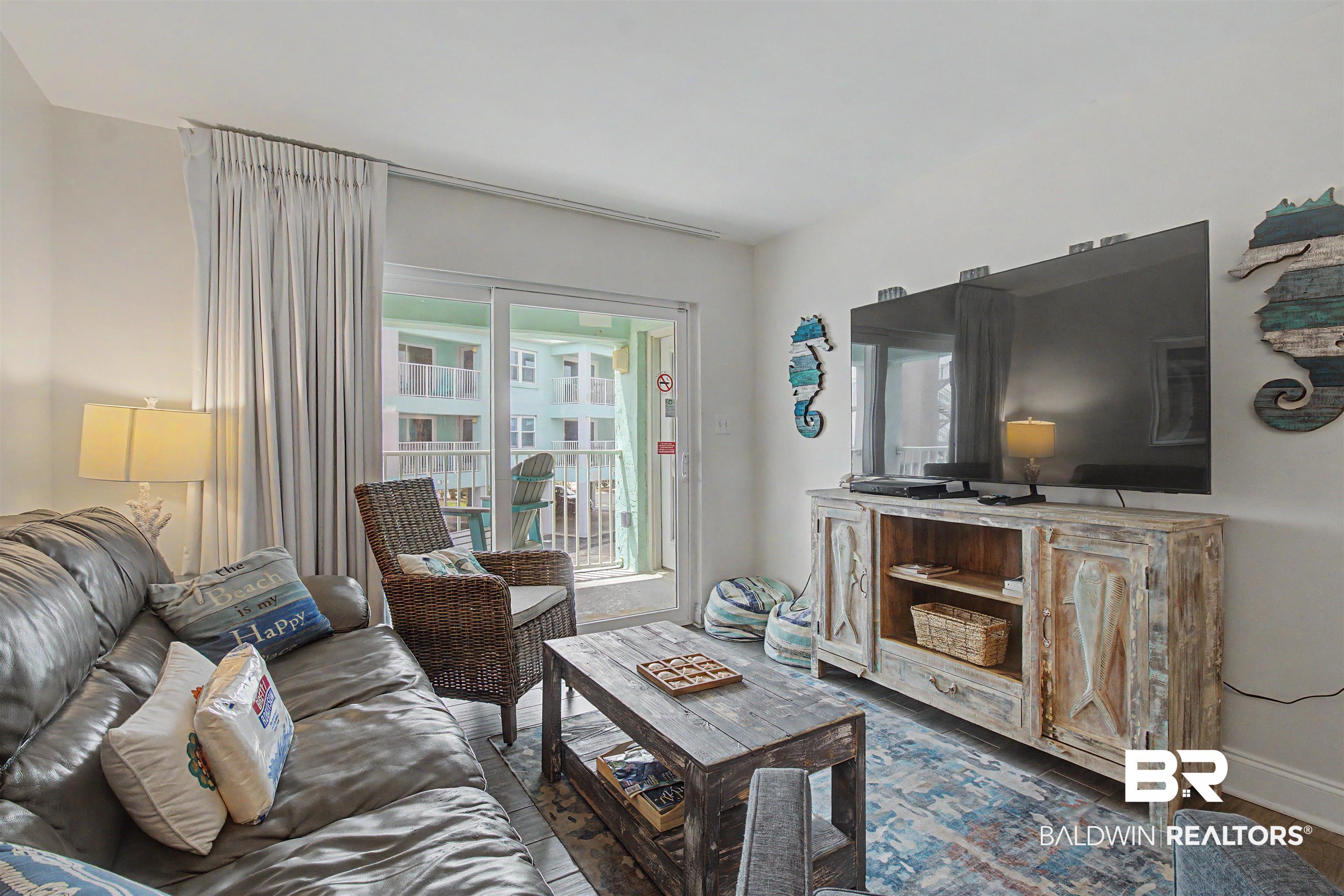 Image 2: Living area featuring wood-finish flooring and a sliding glass door opening to a balcony
