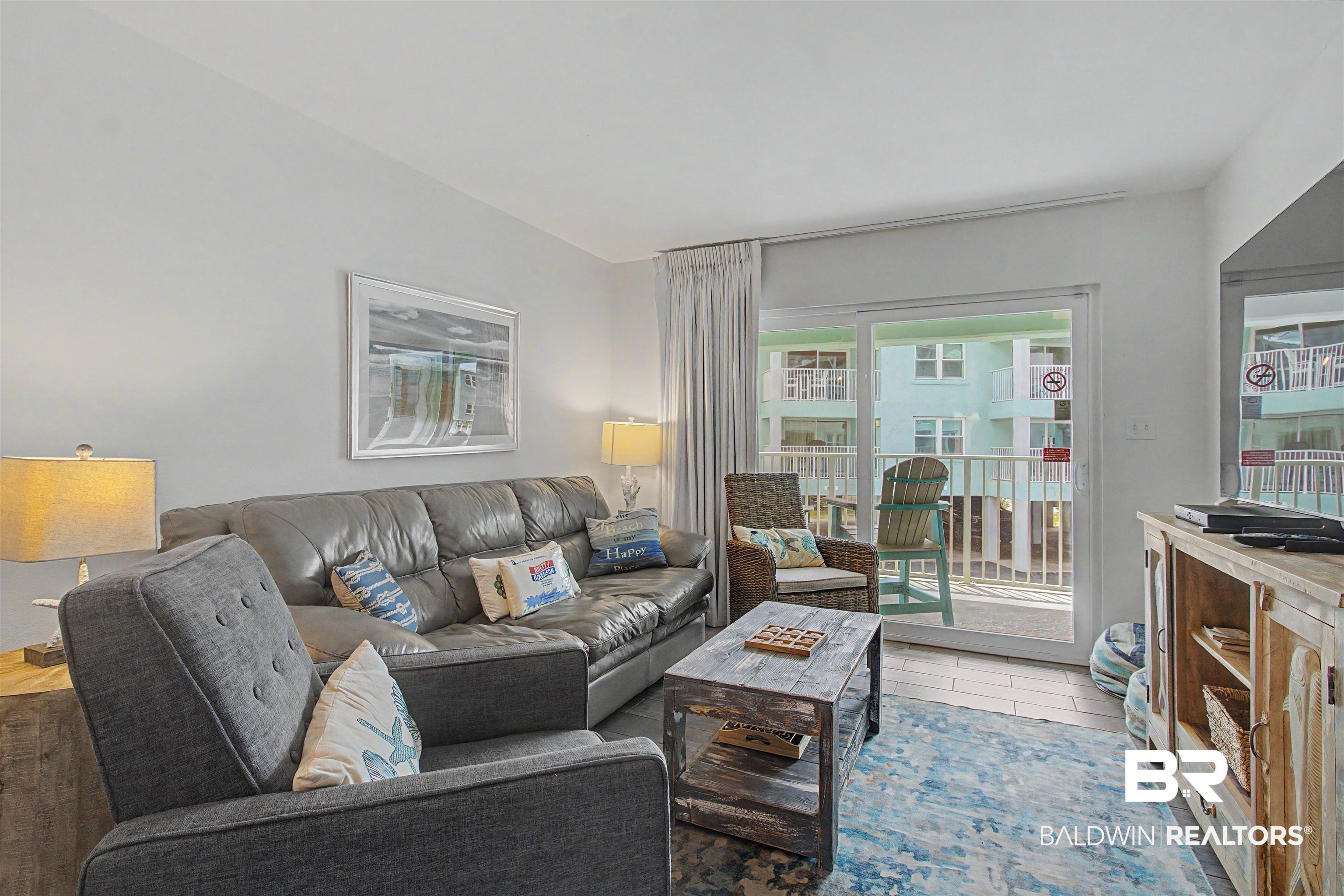 Image 3: Living area featuring wood-finish flooring, a sliding glass door to an outdoor space, and white wall finishes