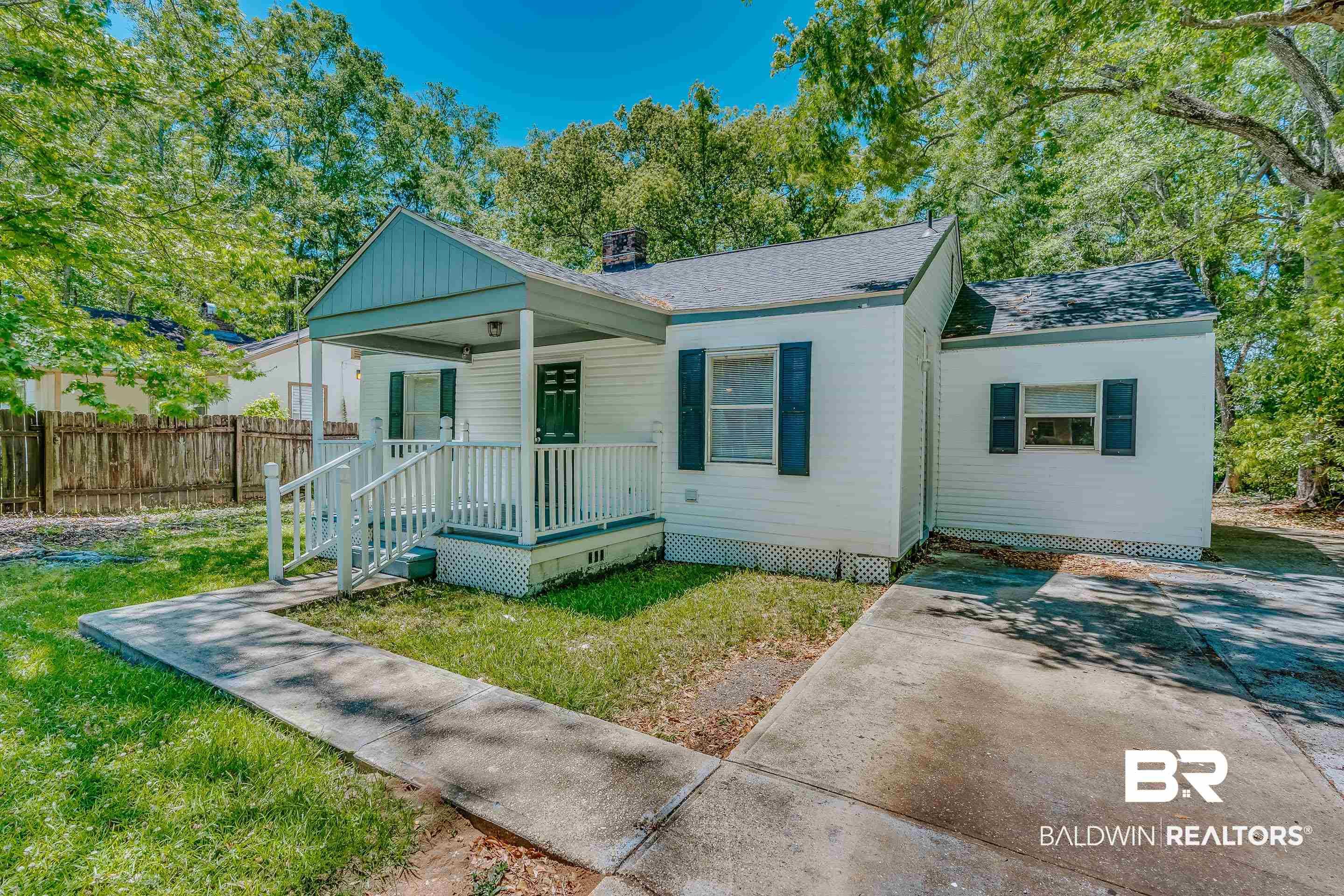Image 2: White exterior home featuring a covered front porch with white railings, a concrete walkway, and a concrete driveway