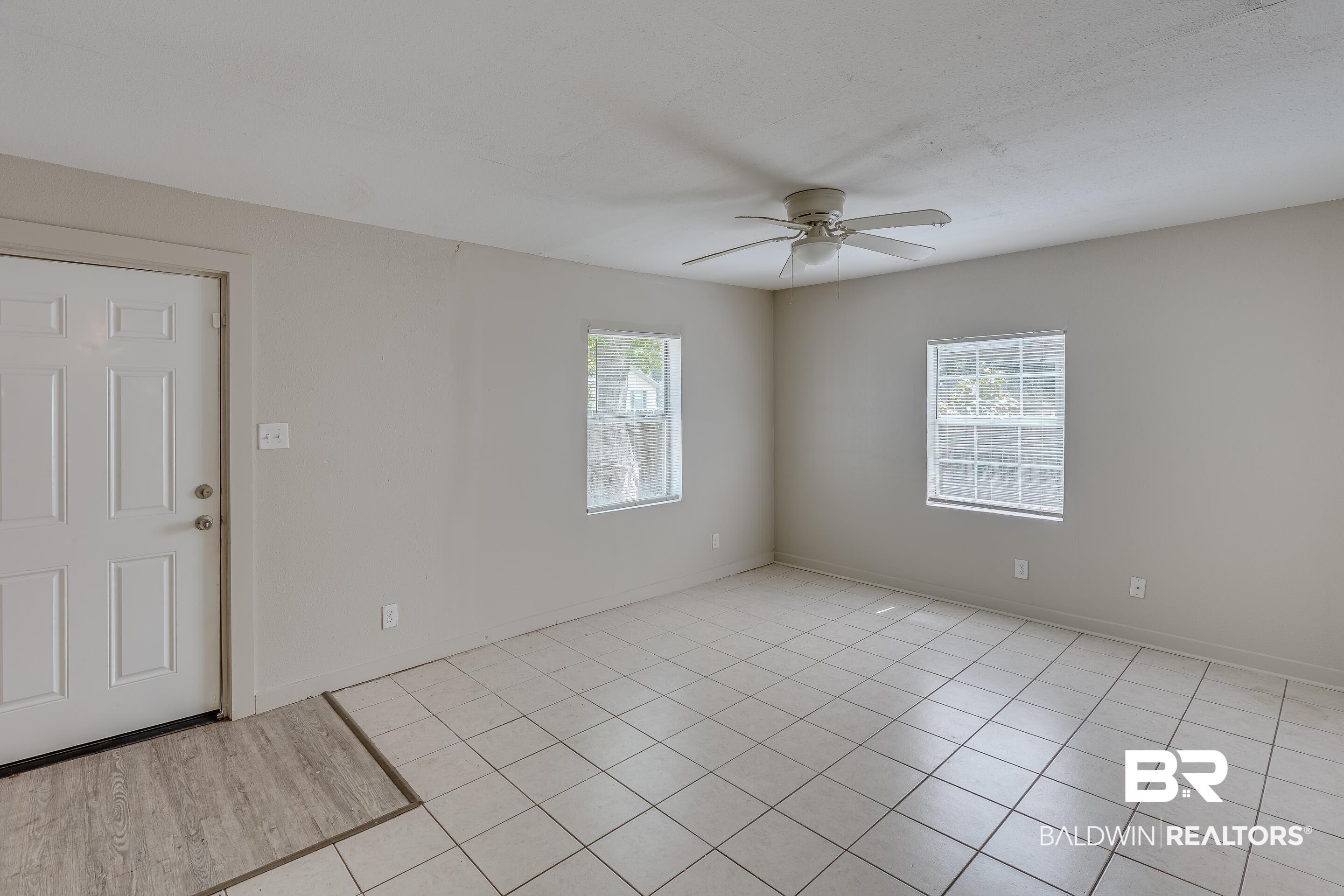 Image 4: Spacious room featuring light-colored tile flooring, neutral wall paint, and multiple windows