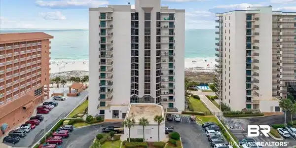Image 2: View of apartment building / complex featuring view of water and beach and uncovered parking