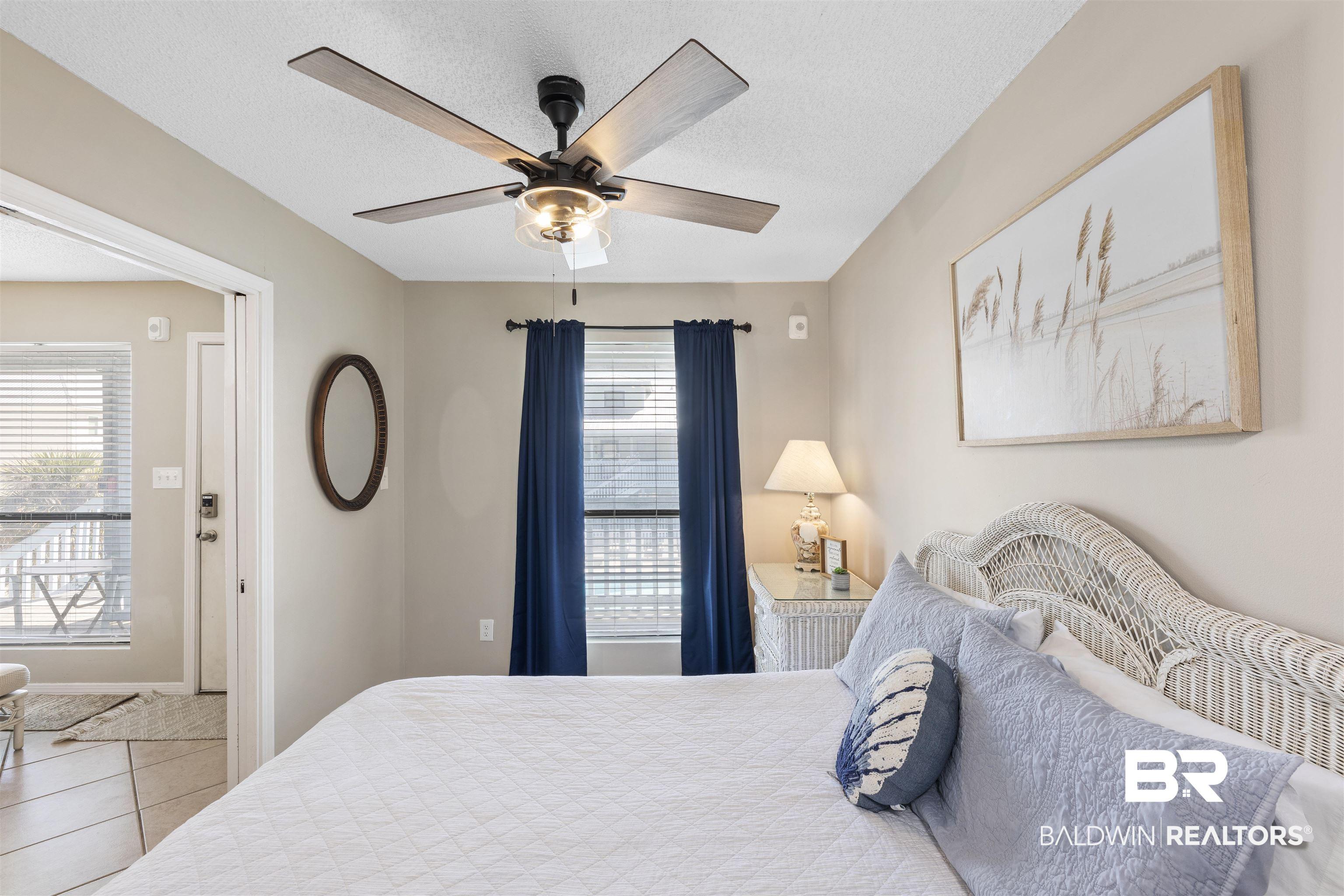 Image 2: Bedroom with a ceiling fan, multiple windows, a textured ceiling, and light tile patterned floors