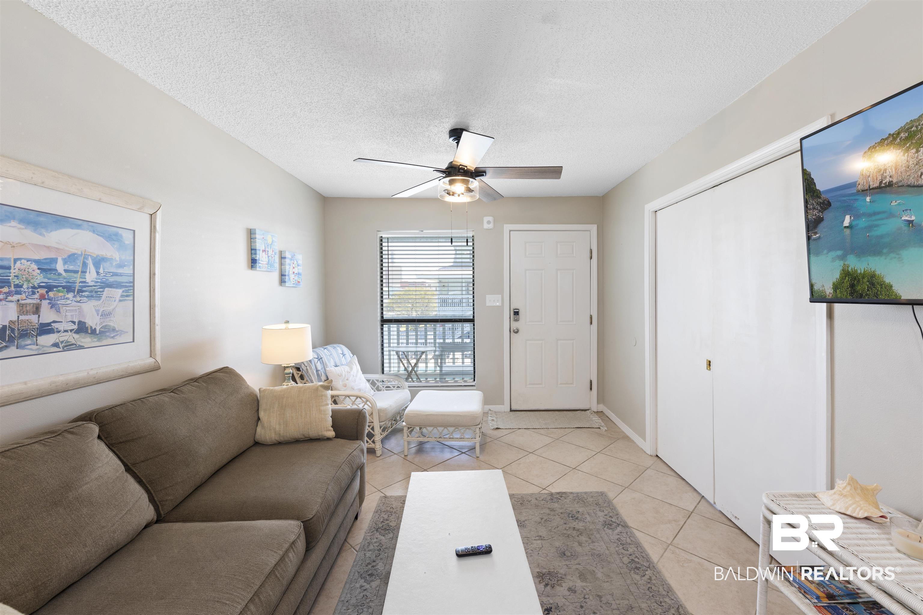 Image 3: Living area featuring ceiling fan, a textured ceiling, and light tile patterned flooring