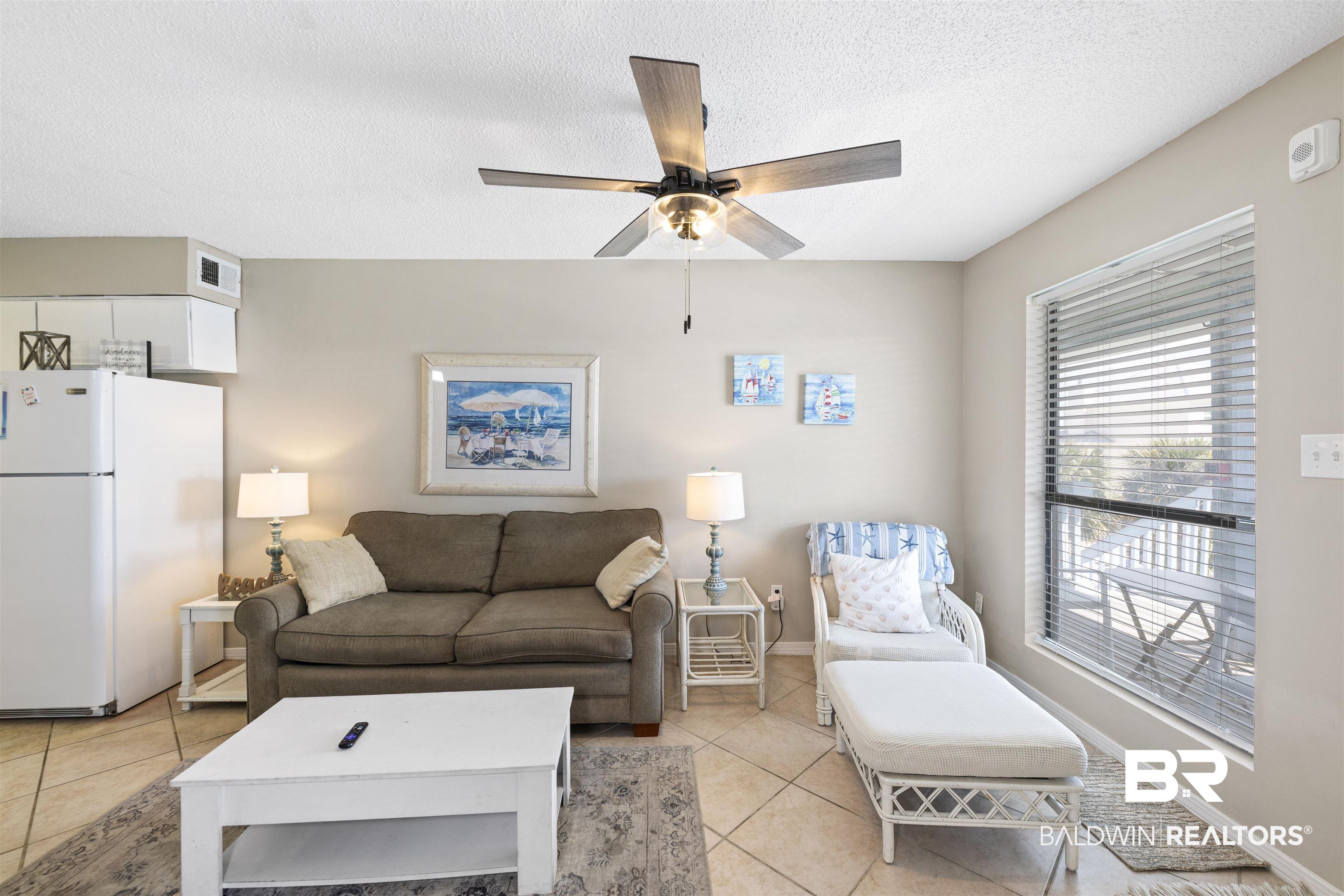 Image 4: Living area with a ceiling fan, a textured ceiling, and light tile patterned floors