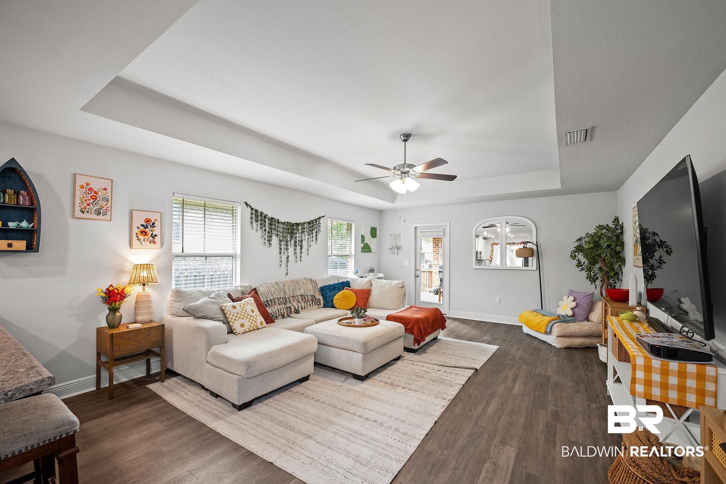 Image 2: Living room with a tray ceiling, dark wood finished floors, and ceiling fan