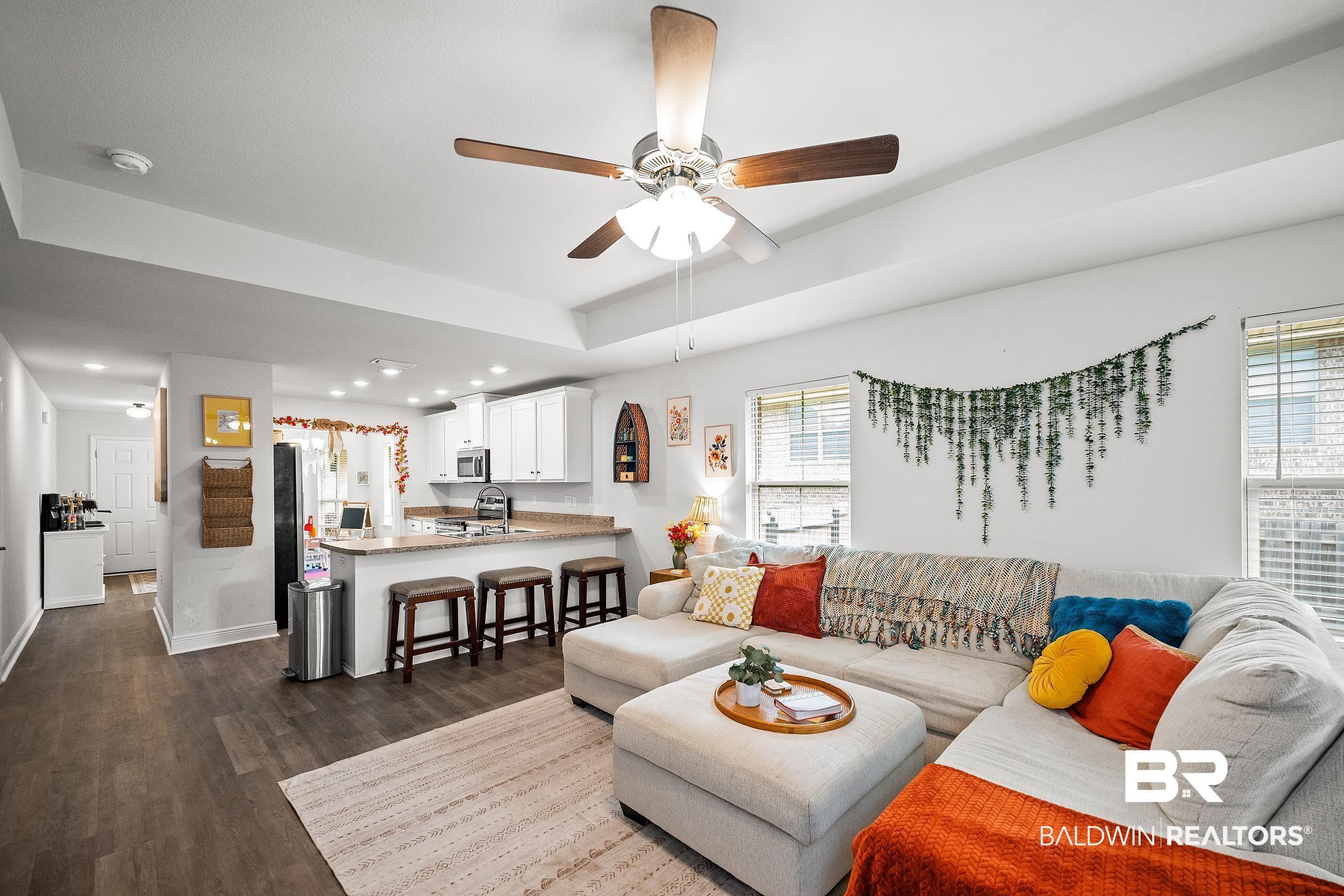 Image 4: Living room with a ceiling fan, dark wood-style flooring, and a raised ceiling