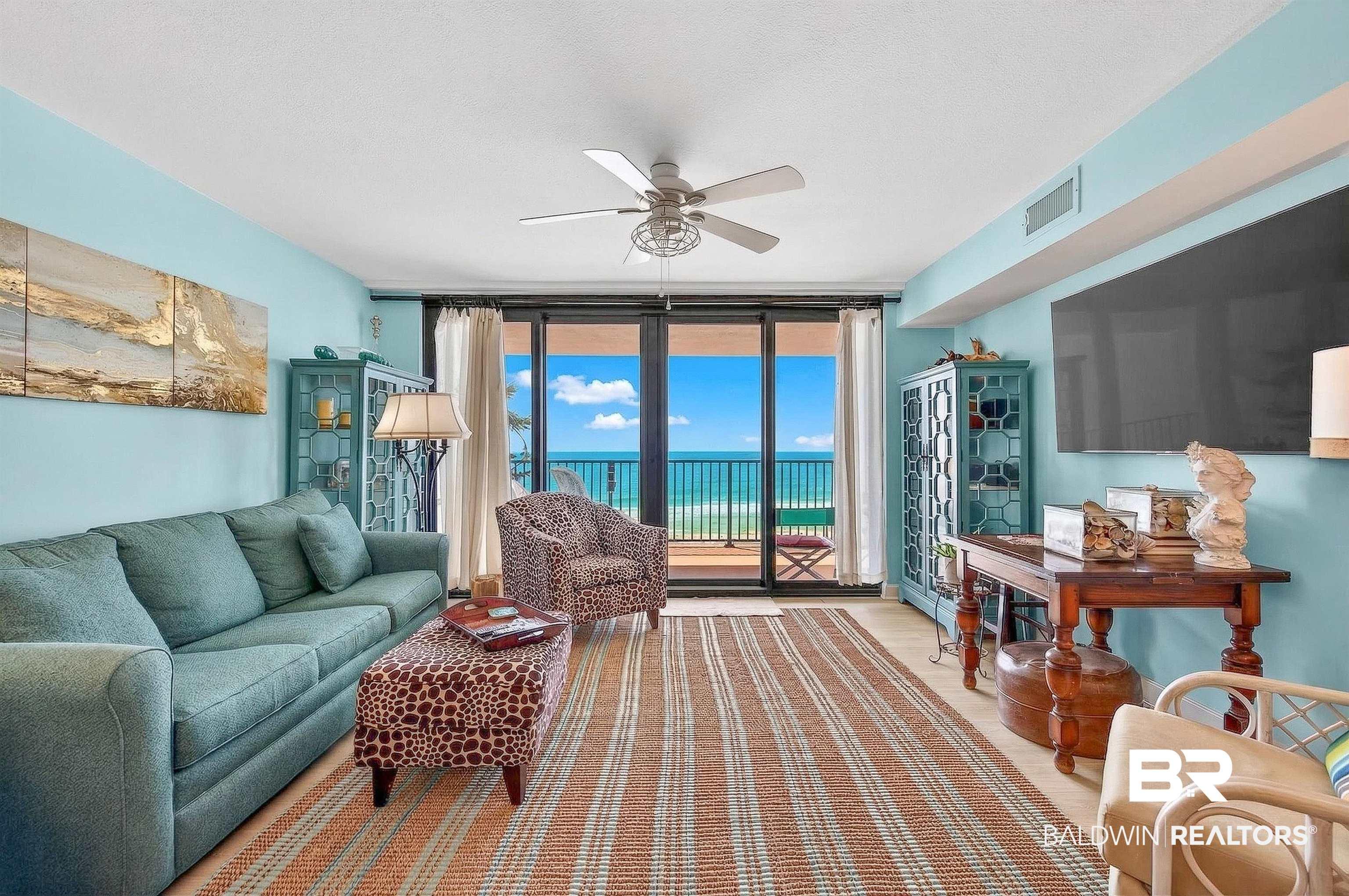 Image 4: Living area featuring expansive windows and ceiling fan