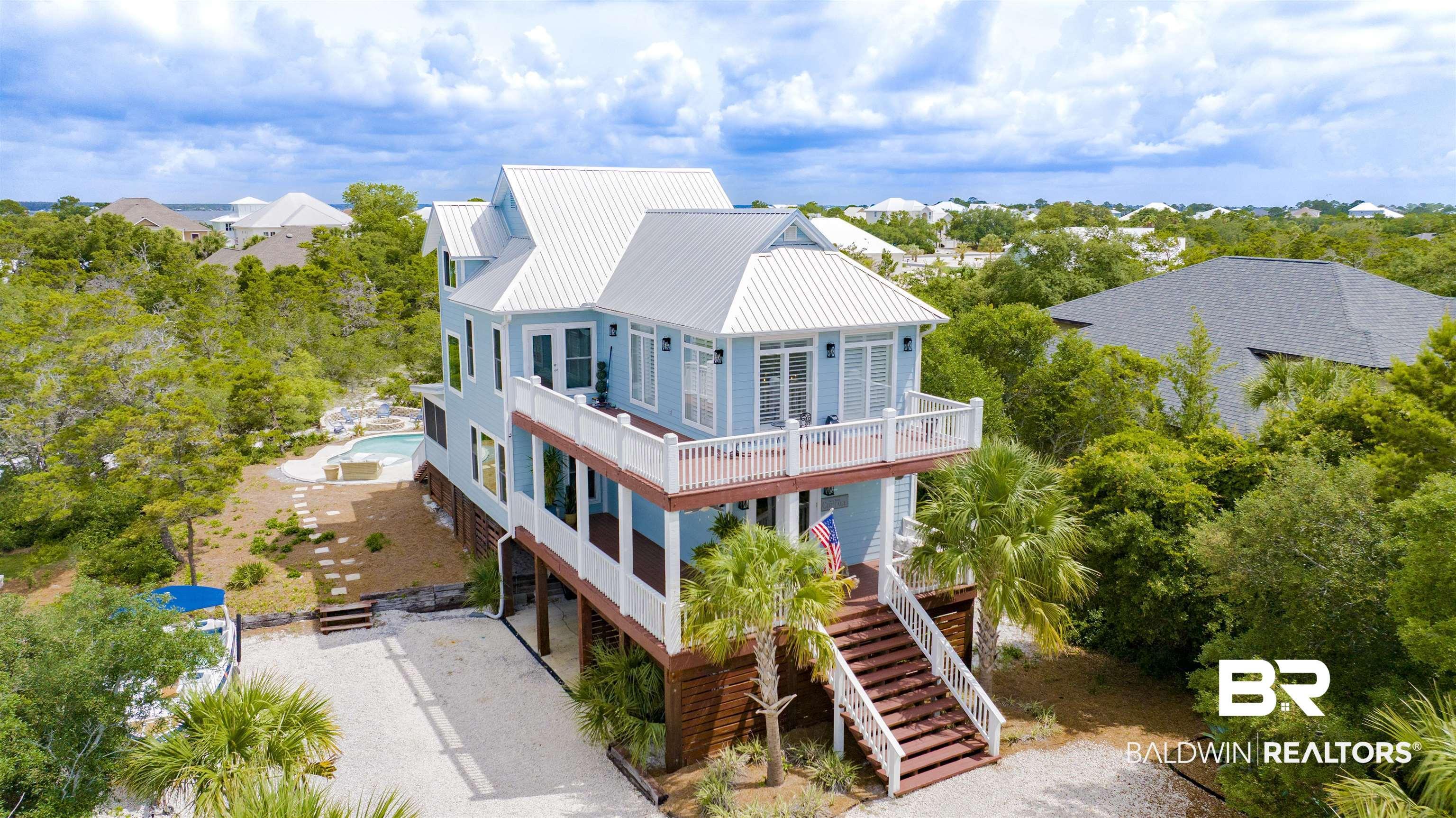 Image 1: Light blue multi-story residence with a metal roof and elevated decks