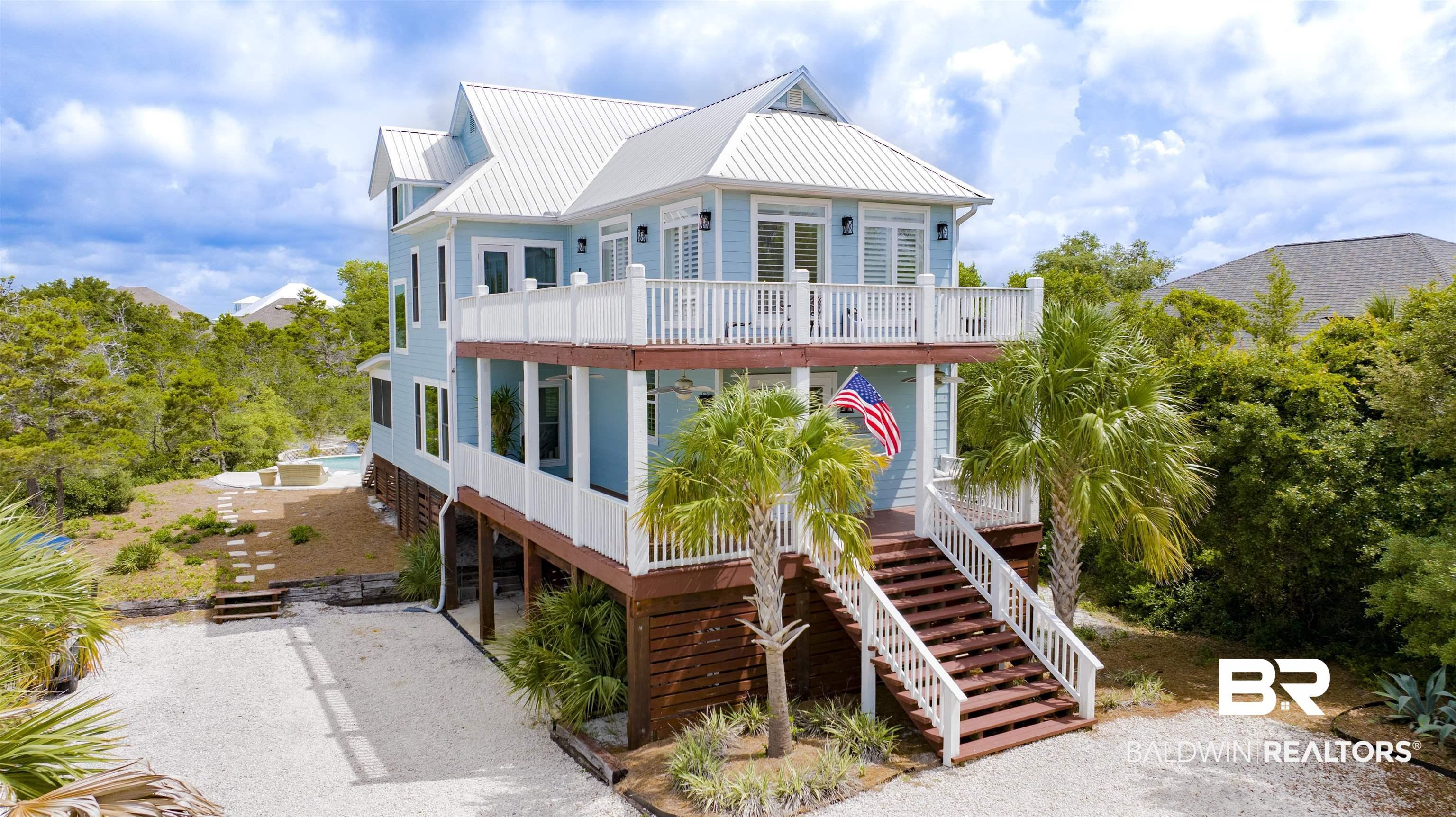 Image 2: Coastal-inspired residence featuring light blue siding and a white metal roof