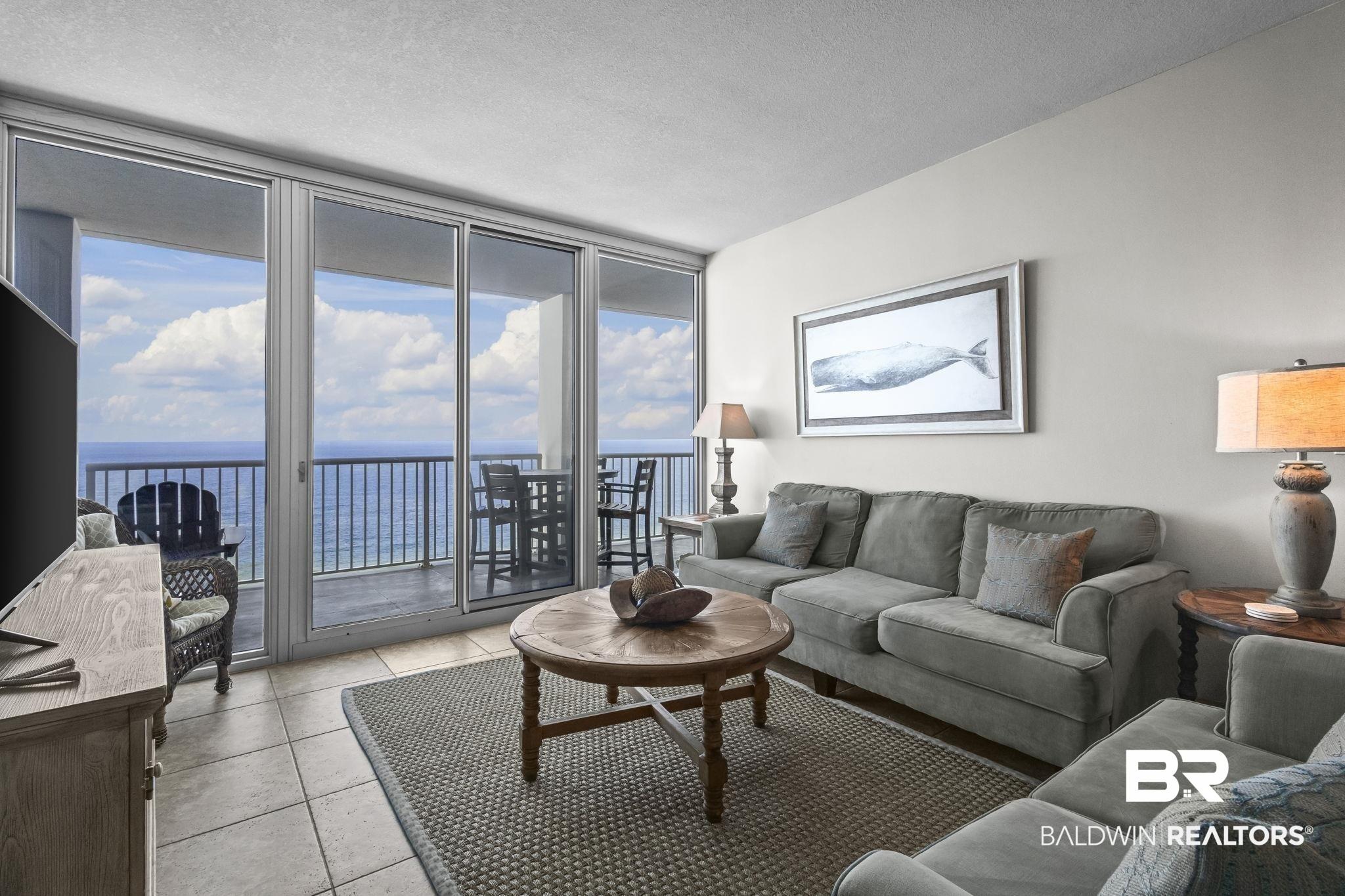 Image 2: Living area with floor to ceiling windows, healthy amount of natural light, a water view, light tile patterned floors, and a textured ceiling