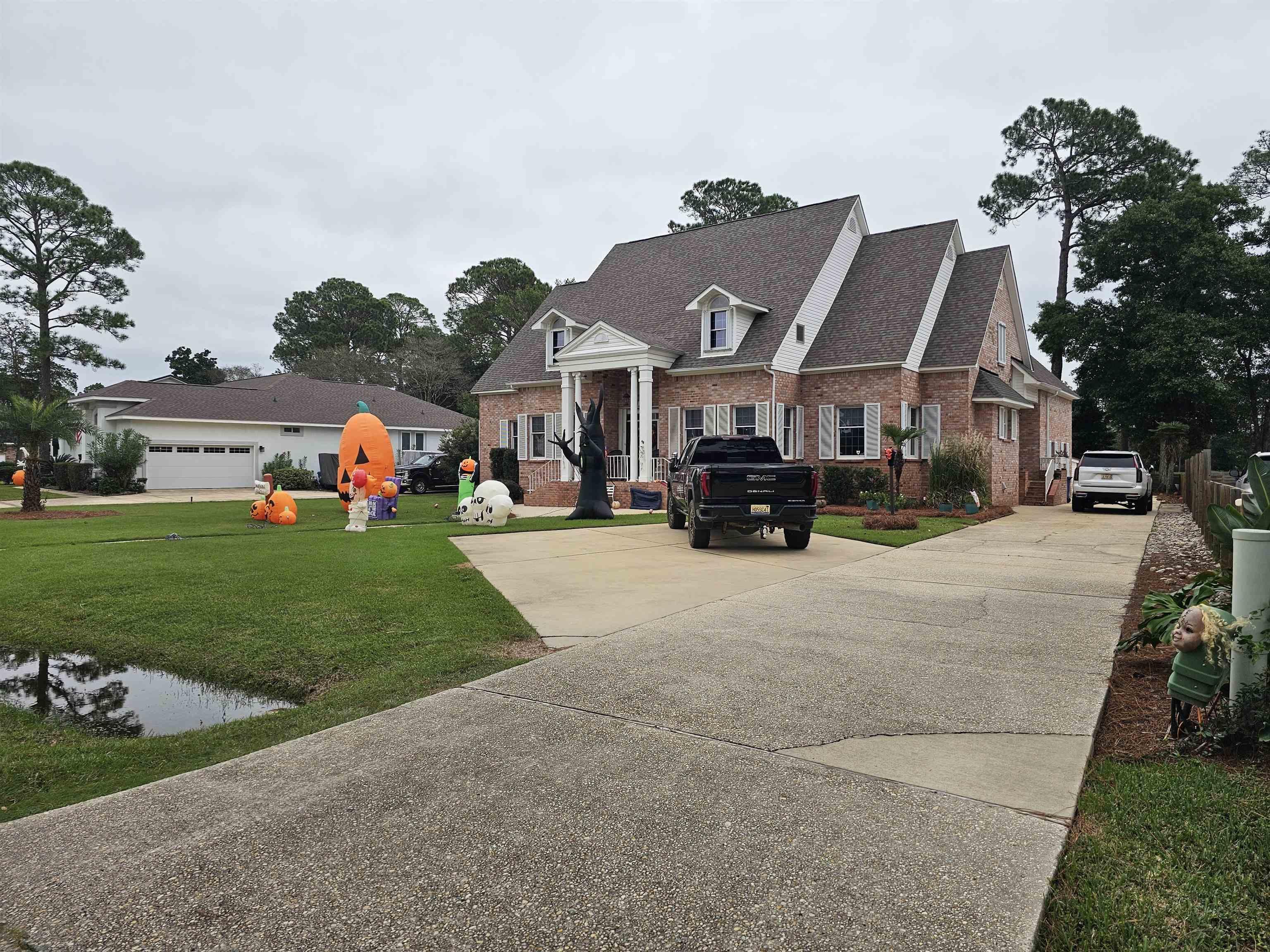 Image 1: View of front of home featuring brick siding, driveway, a front yard, and roof with shingles
