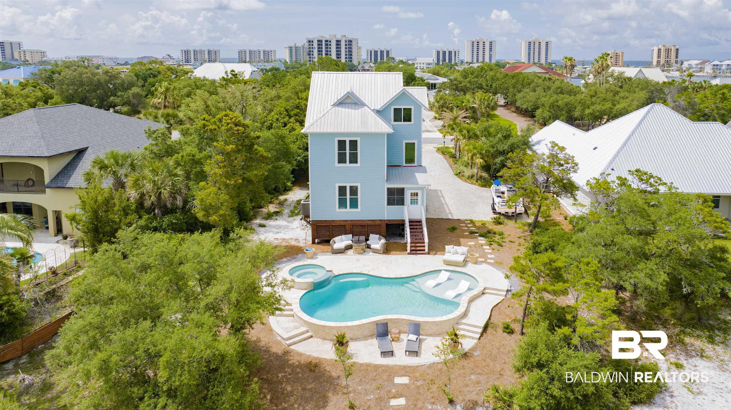 Image 3: Elevated coastal residence featuring a light blue exterior and a white metal roof