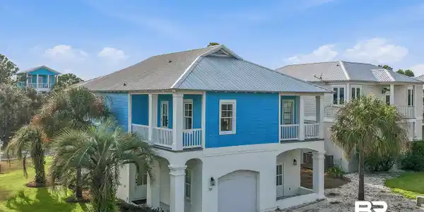 Image 4: Blue siding exterior with white trim and a metal roof